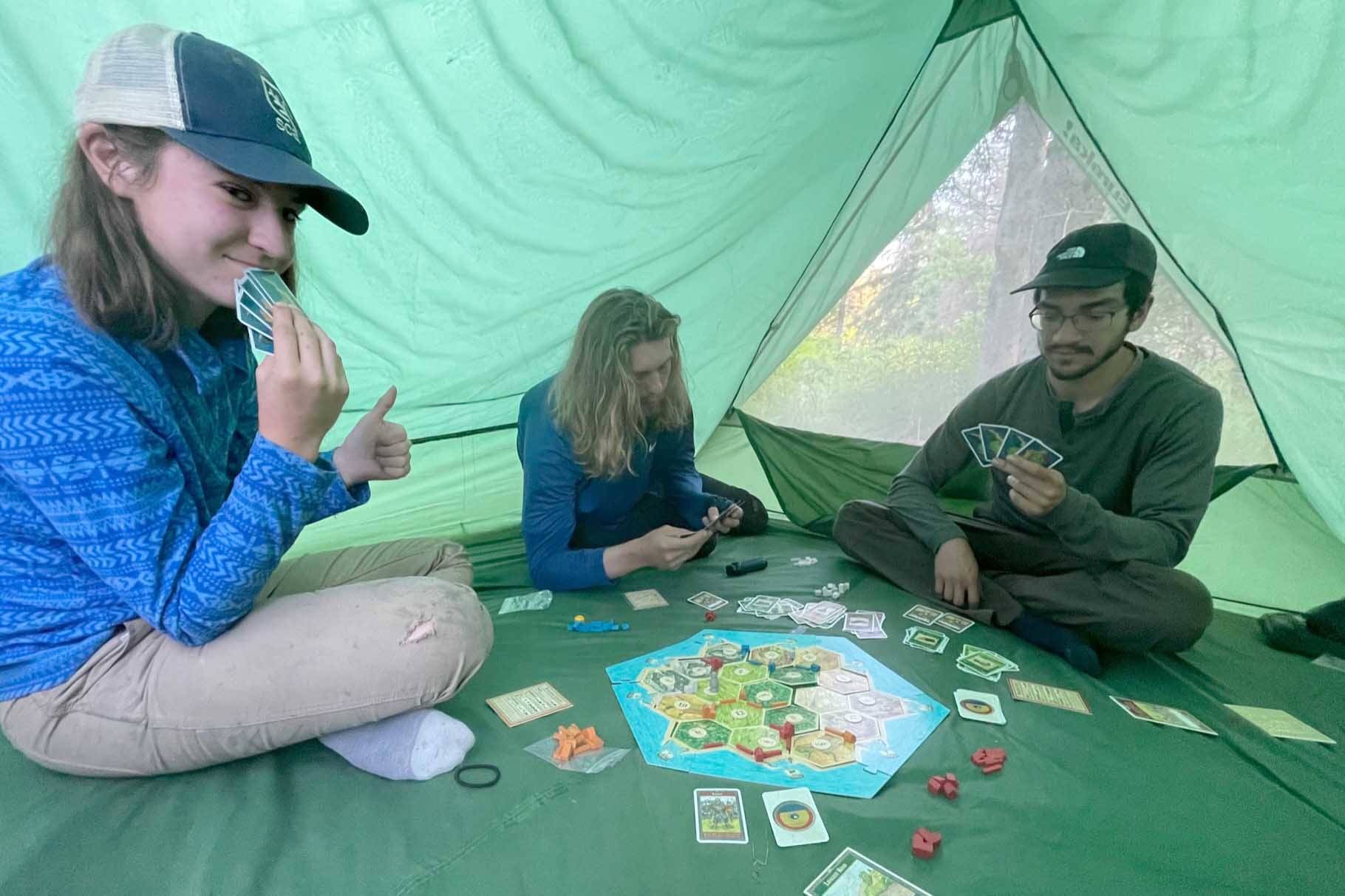 A Student Conservation Association team builds traditions around a game of Catan in a tent by Funny River. (Photo by US Fish and Wildlife Service)