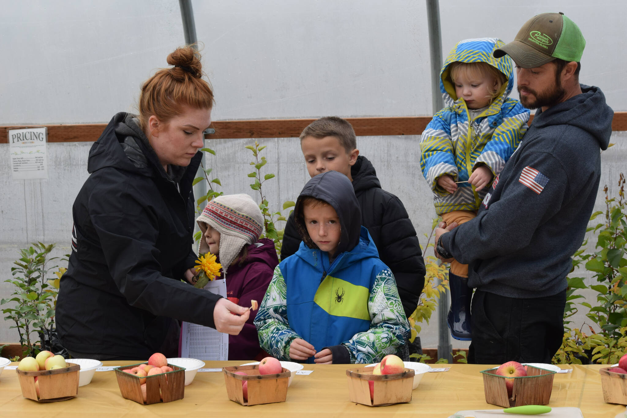 The Tonione family tastes apples at O’Brien Garden and Trees in Nikiski, Alaska, on Saturday, Sept. 25, 2021. (Camille Botello/Peninsula Clarion)