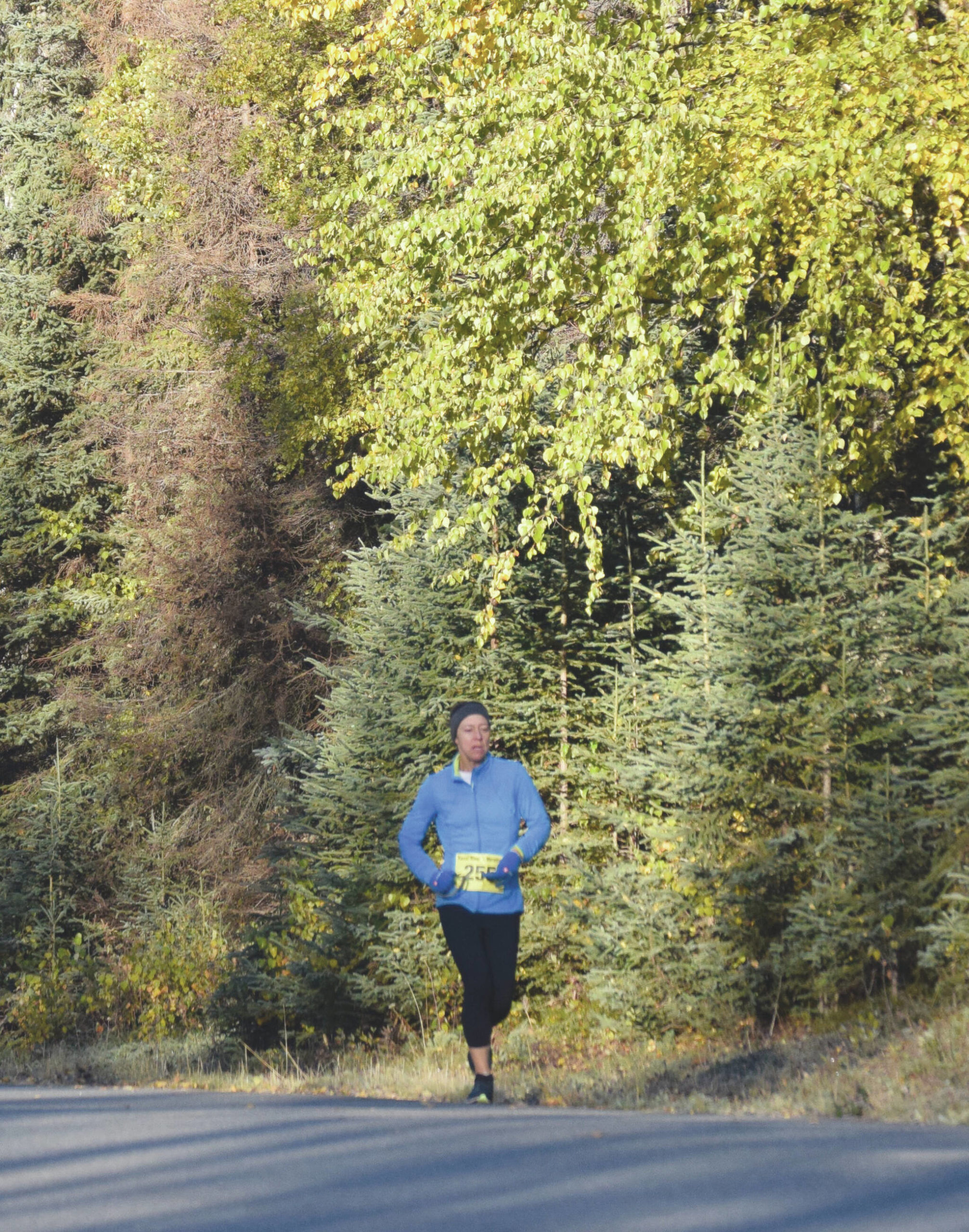 Women’s half marathon winner Meghan Cloud is awash in fall colors during the Kenai River Marathon in Kenai, Alaska, on Sunday, Sept. 26, 2021. (Photo by Jeff Helminiak/Peninsula Clarion)