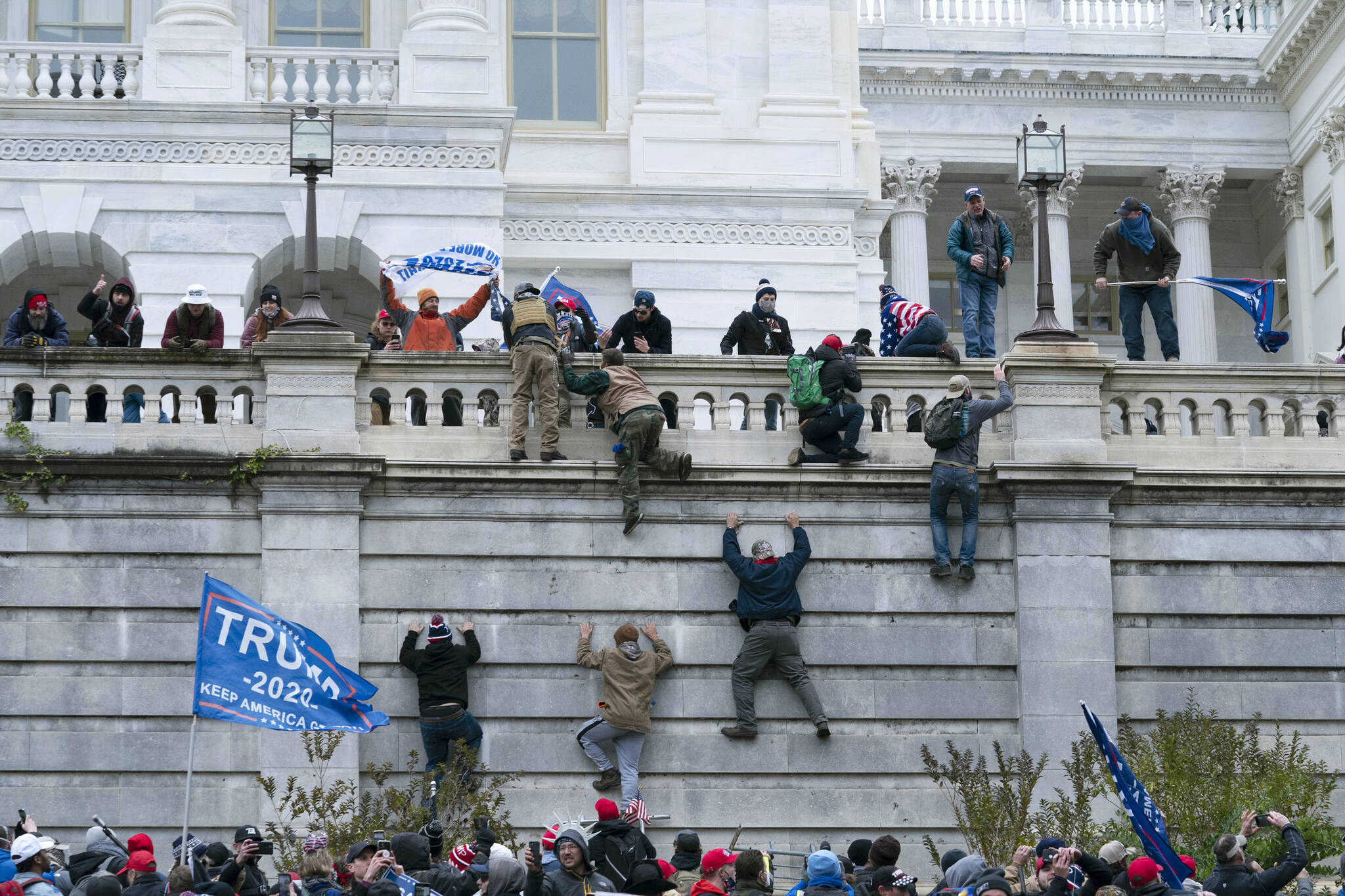 In this Jan. 6, 2021 file photo, supporters of then President Donald Trump climb the west wall of the the U.S. Capitol in Washington. A New York mother and son have been charged with theft in aiding the disappearance of House Speaker Nancy Pelosi’s laptop during the Jan. 6 insurrection after the FBI initially raided a home 4,500 miles away in Alaska, looking for the computer. According to court documents, the FBI on Friday, Oct. 1 arrested Maryann Mooney-Rondon, and her son, Rafael Rondon, of Watertown, N.Y. Both also face other charges related to the riot at the Capitol. (AP Photo/Jose Luis Magana, File)