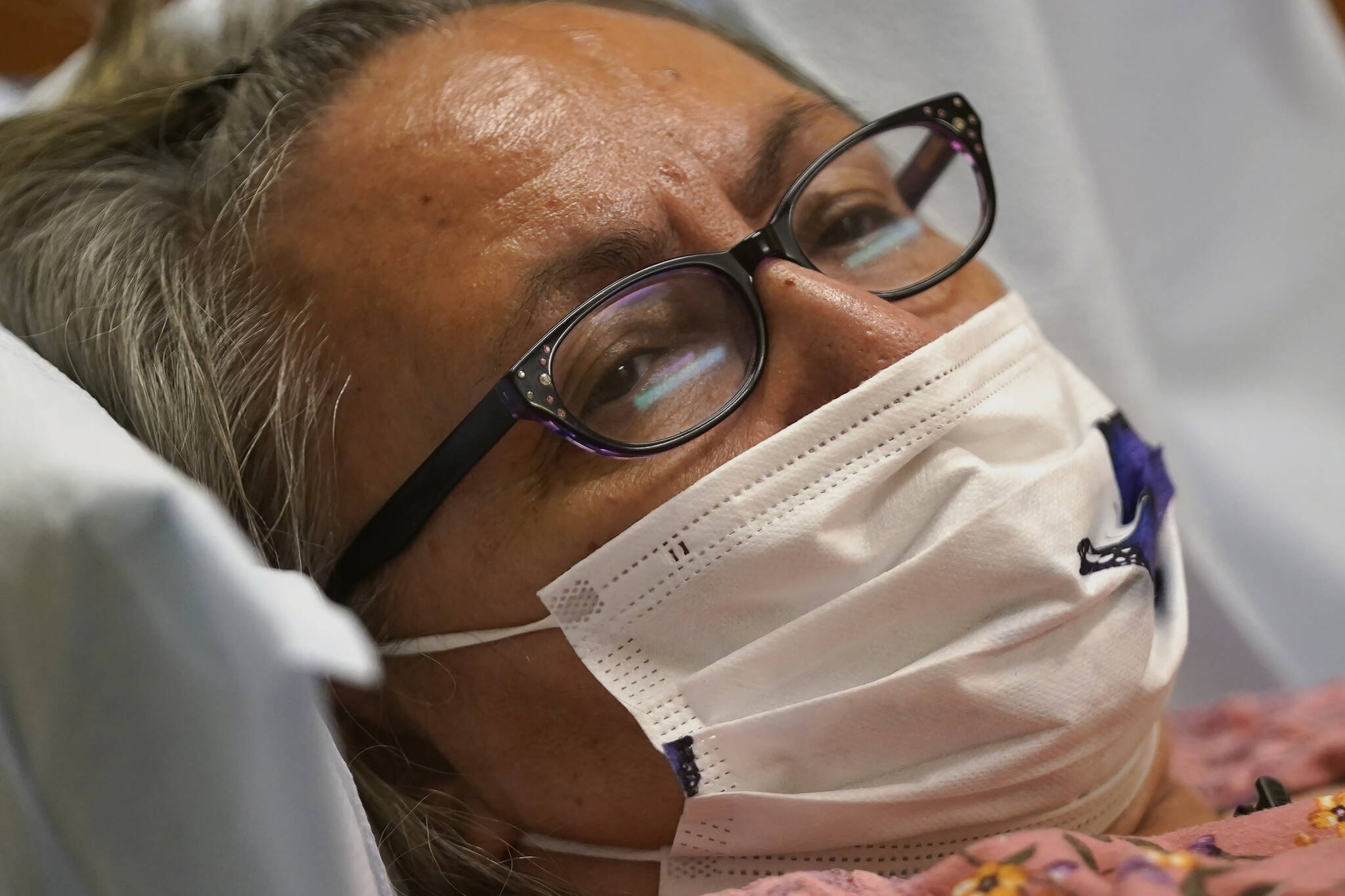 Joyce Johnson-Albert looks on as she receives an antibody infusion while lying on a bed in a trauma room at the Upper Tanana Health Center Wednesday, Sept. 22, 2021, in Tok, Alaska. Johnson-Albert was optimistic but also realistic. “I just hope the next few days I’ll be getting a little better than now,” Johnson-Albert told a reporter on the other side of a closed, sliding glass door to the treatment room two days after testing positive for COVID-19 and while receiving an antibody infusion. “It’s just hard to say. You can go either way.” (AP Photo/Rick Bowmer)