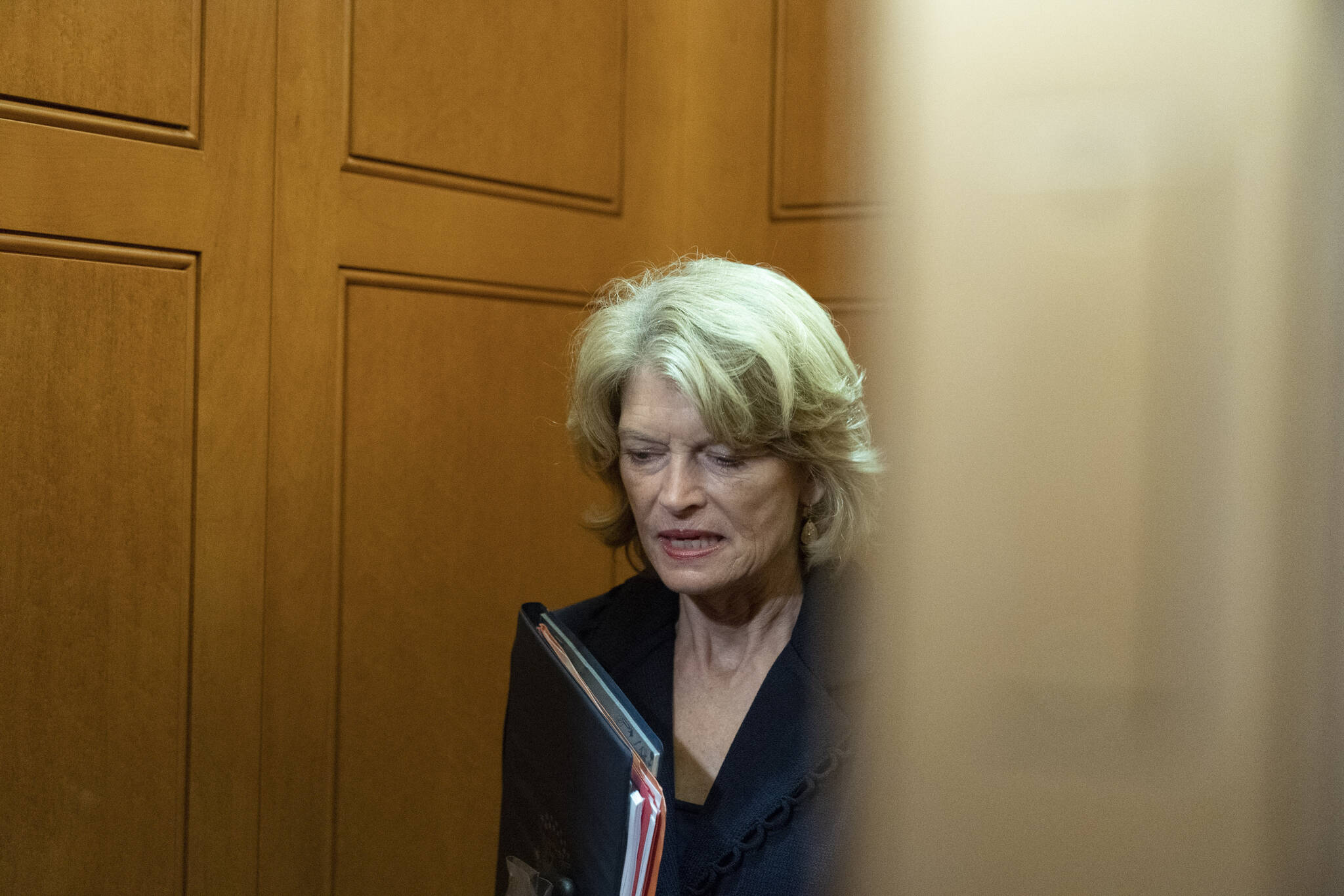 In this Oct. 7, 2021, file photo, Sen. Lisa Murkowski, R-Alaska, stands in an elevator as she departs, on Capitol Hill, in Washington. A man described as a “normal guy” who kept a low profile in his rural Alaska community faces charges he threatened to hire an assassin to kill the U.S. senator. Jay Allen Johnson was scheduled to be arraigned later Friday, Oct. 8, 2021, on charges related to phone threats authorities say he made against Murkowski. Johnson was arrested earlier in the week and was being held in a Fairbanks jail ahead of the federal court hearing. (AP Photo/Alex Brandon, File)