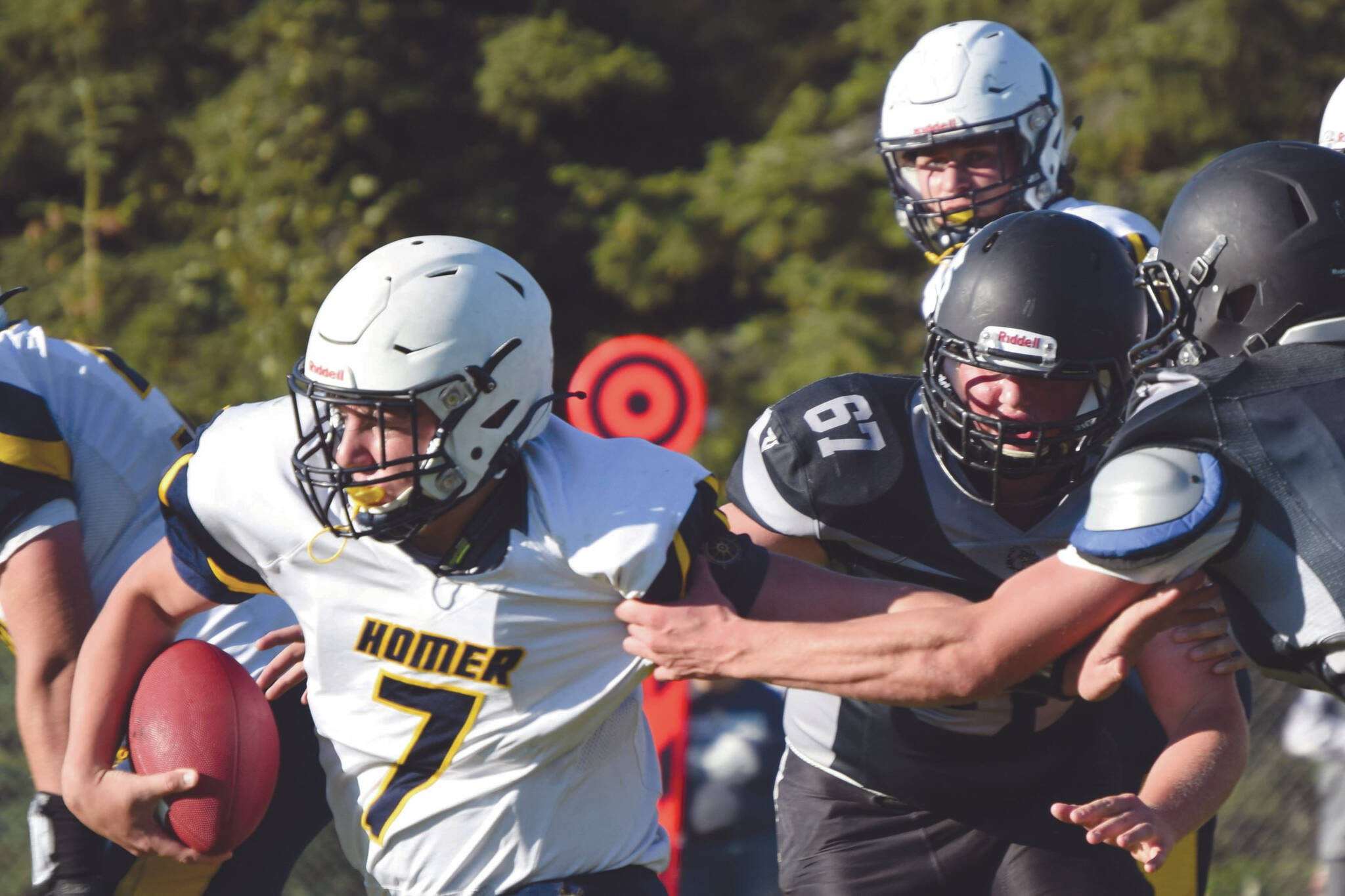 Homer’s Carter Tennison rushes past Nikiski’s Charlie Chamberlain and Koleman McCaughey on Friday, Sept. 11, 2020, at Nikiski High School in Nikiski, Alaska. (Photo by Jeff Helminiak/Peninsula Clarion)