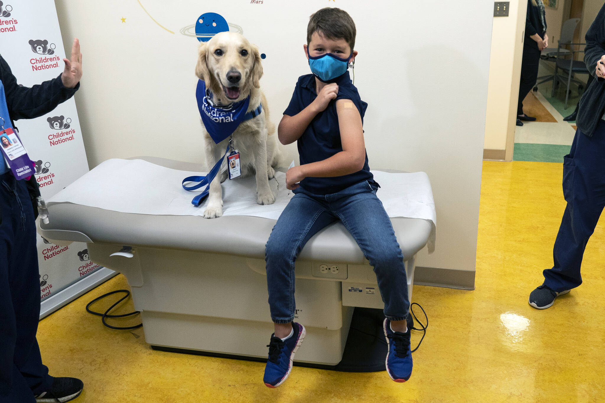 Carter Giglio, 8, joined by service dog Barney of Hero Dogs, shows off the bandaid over his injection site after being vaccinated, Wednesday, Nov. 3, 2021, at Children’s National Hospital in Washington. The U.S. enters a new phase Wednesday in its COVID-19 vaccination campaign, with shots now available to millions of elementary-age children in what health officials hailed as a major breakthrough after more than 18 months of illness, hospitalizations, deaths and disrupted education. (AP Photo/Carolyn Kaster)