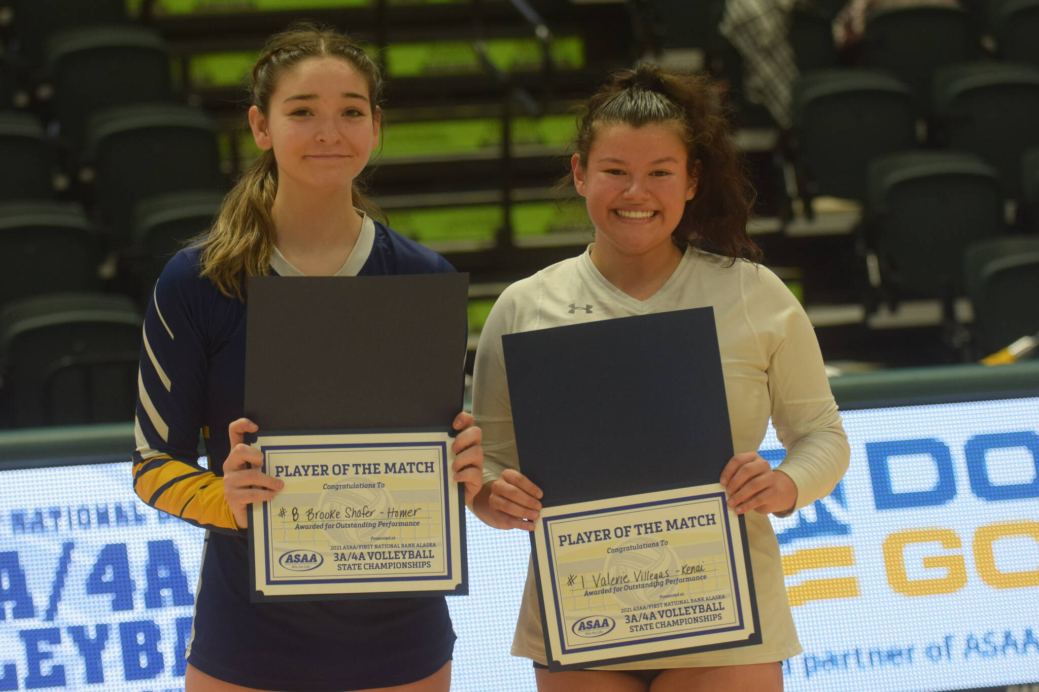 Homer’s Brooke Shafer and Kenai’s Valerie Villegas win the players of the match award at the end of the 3A state volleyball consolation game at the Alaska Airlines Center in Anchorage on Saturday, Nov. 13, 2021. (Camille Botello/Peninsula Clarion)