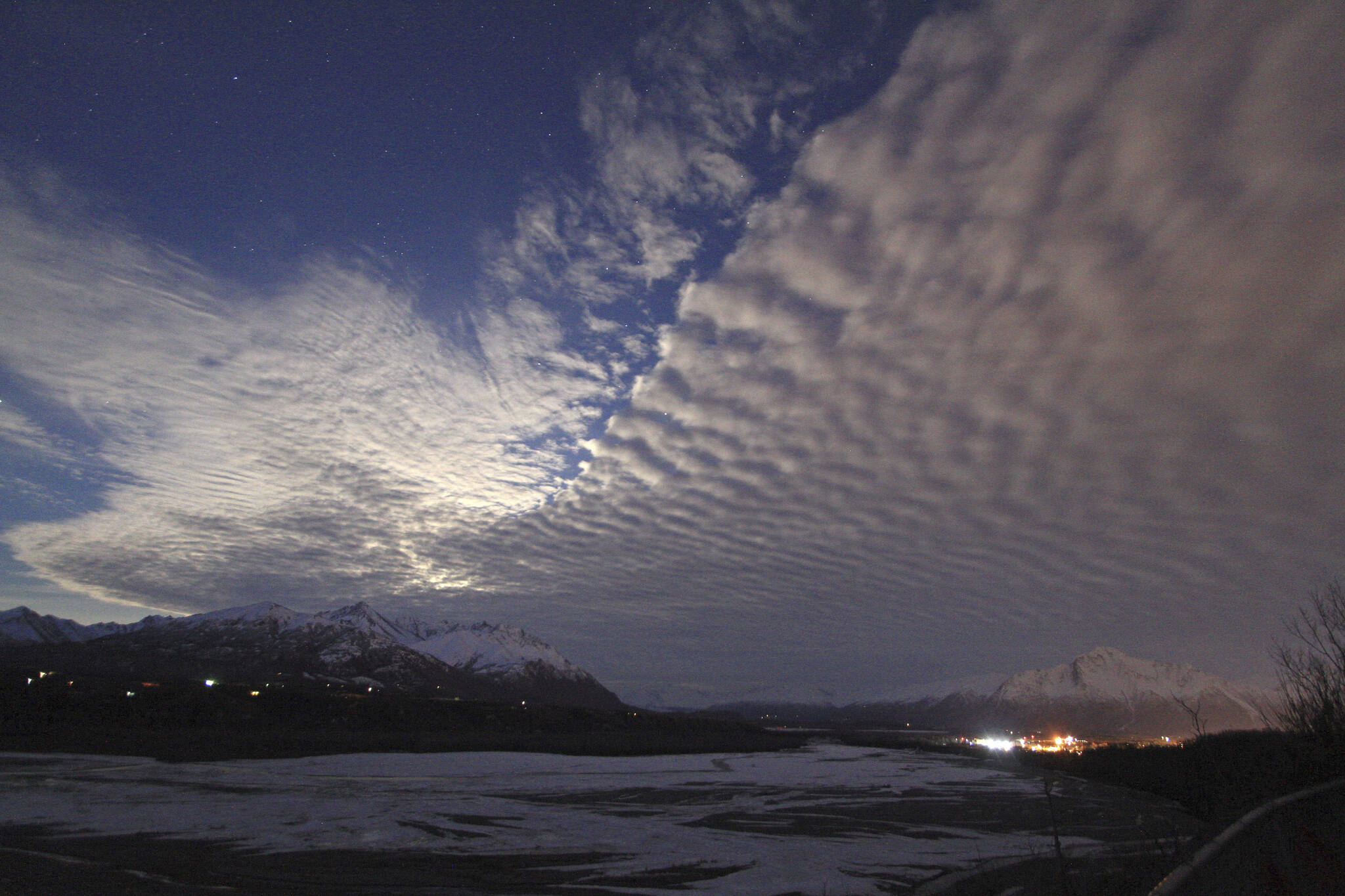 Clouds over the sky over Lazy Mountain and the Matanuska River on March 23, 2016, in Palmer, Alaska. Lights from downtown Palmer and Pioneer Peak can be seen in the lower right. Some critics say a new map of state political boundaries drawn following the last Census short-changes the fast-growing area north of Anchorage seen as a hotbed of conservatism. (AP Photo/Dan Joling, File)