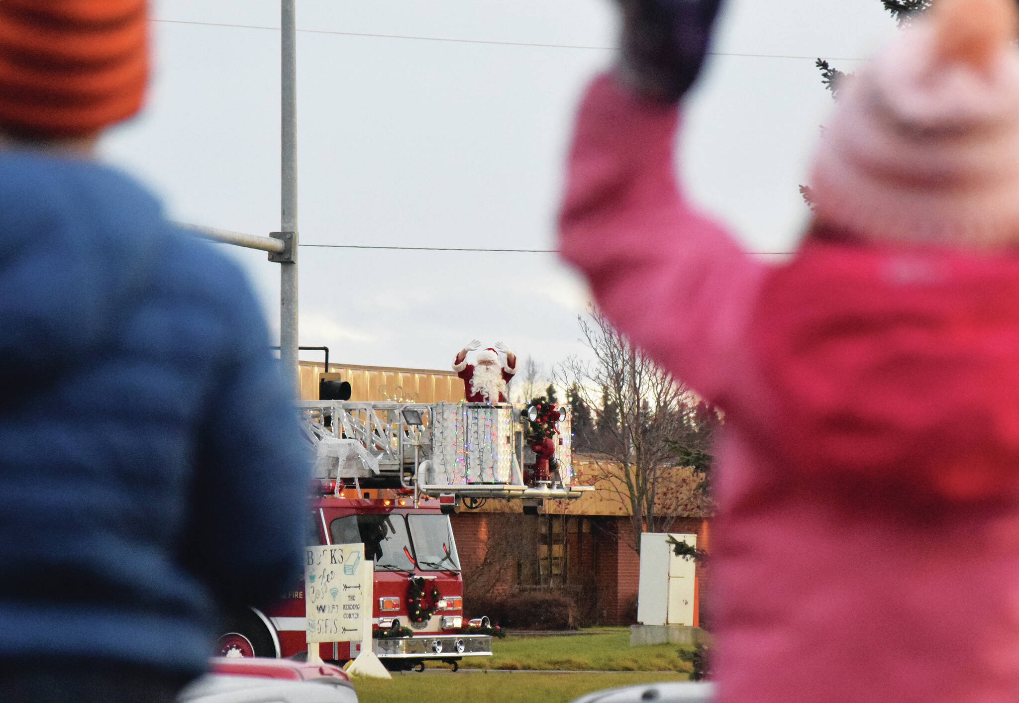 Children wave as Santa Claus arrives on top of a firetruck Friday, Nov. 29, 2019, at the Christmas Comes to Kenai celebration at the Kenai Visitor and Cultural Center. (Photo by Joey Klecka/Peninsula Clarion)