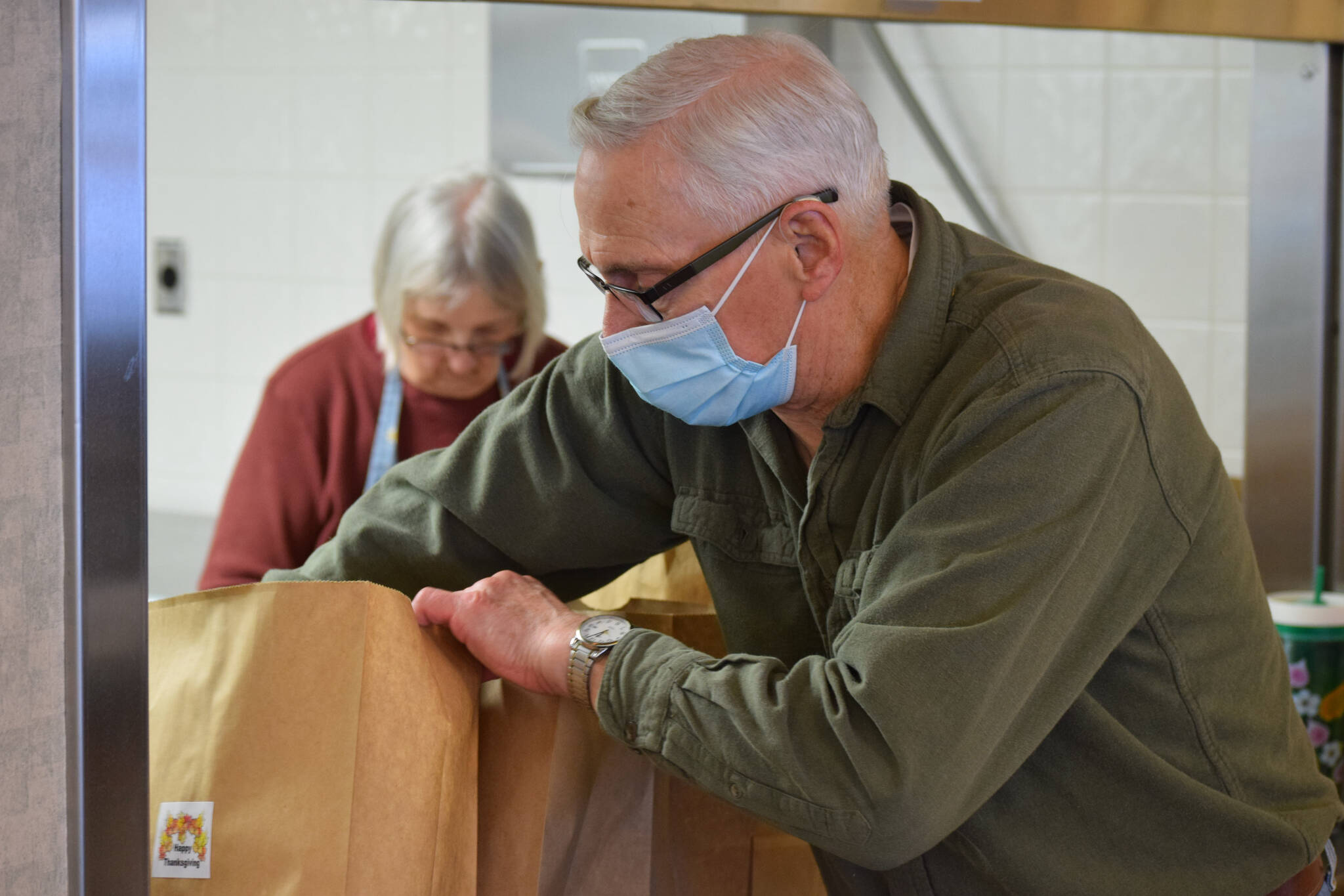 Kenai Senior Center volunteer Carol Freas, left, and driver Don Erwin prepare to-go Thanksgiving meals at the center on Tuesday, Nov. 23, 2021. (Camille Botello/Peninsula Clarion)