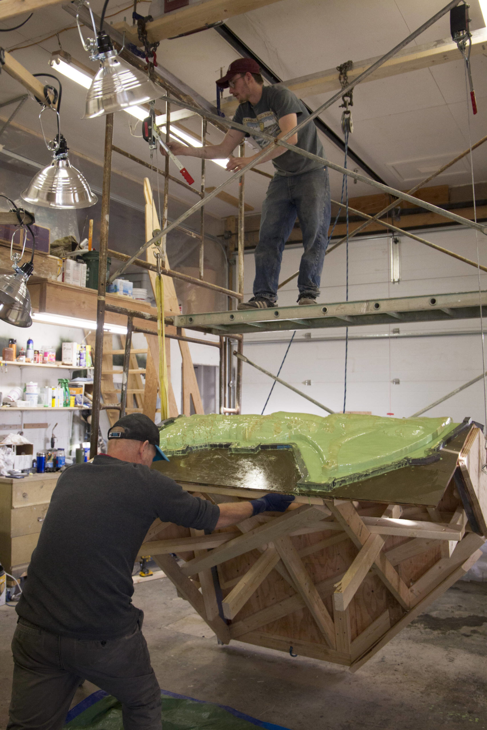 Matt (above) and Rob Wiard (below) lift the bench mold in order to rotate it for an additional layer of rubber to be poured on the clay. (Photo by Sarah Knapp/Homer News)