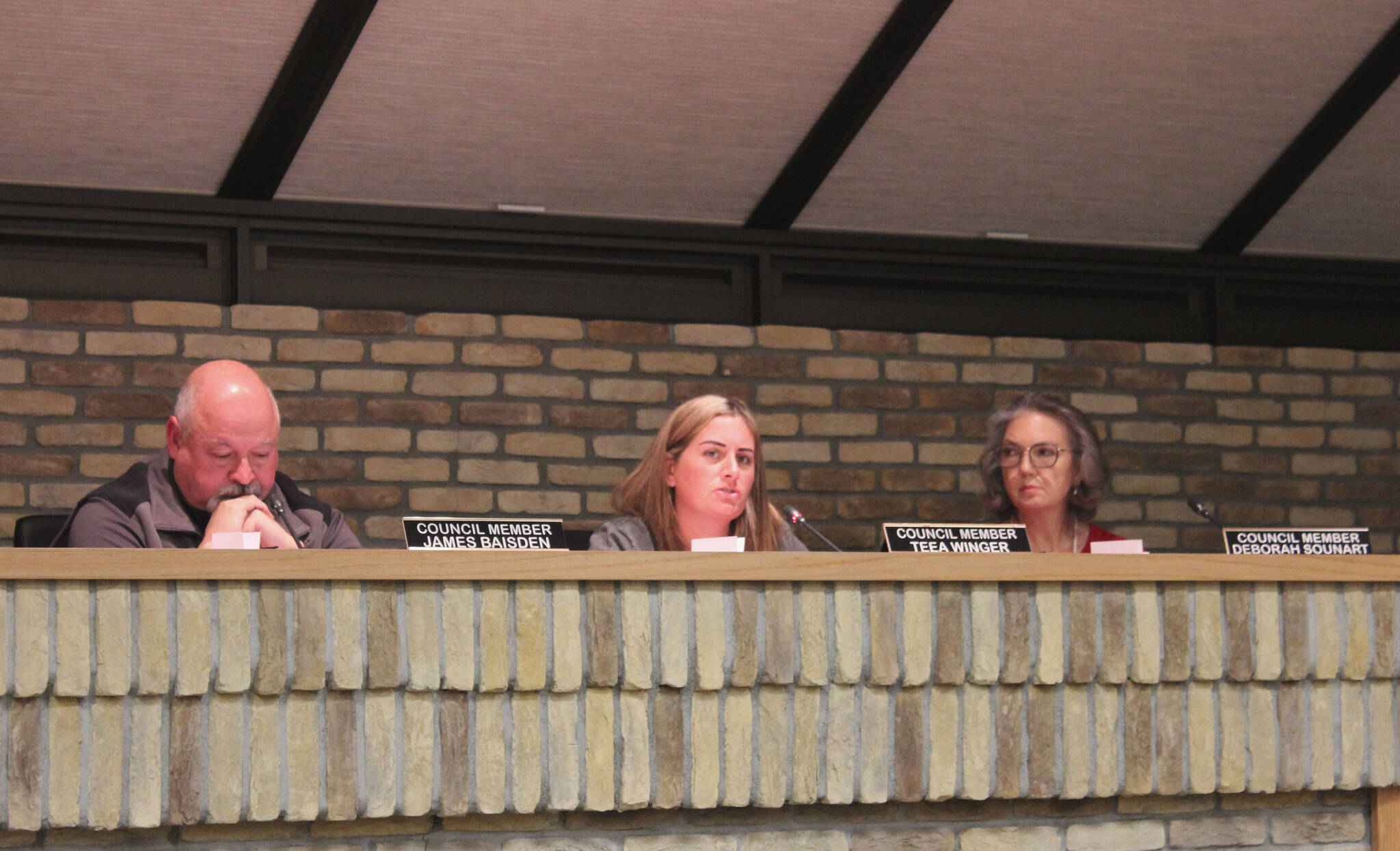 Kenai City Council members James Baisden (left) and Deborah Sounart (right) listen as member Teea Winger (center) speaks in support of legislation opposing government COVID-19 mandates, during a meeting of the Kenai City Council on Wednesday, in Kenai.