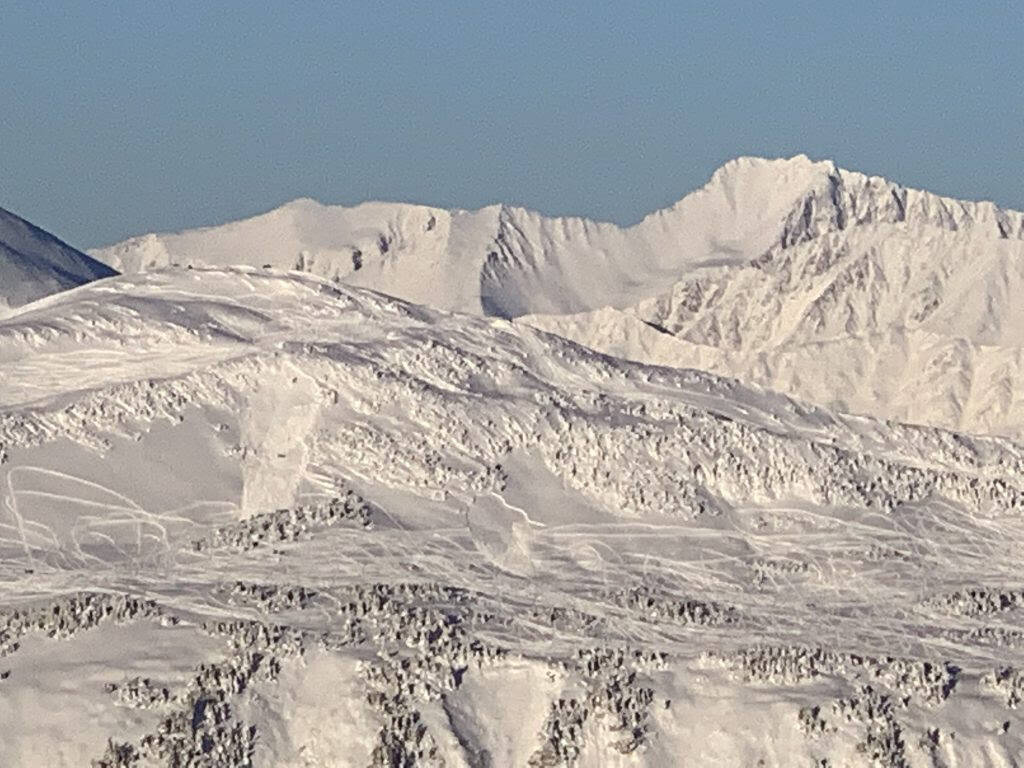 Two snowmachine-triggered snow slabs are seen below the weather station of Seattle Ridge in Turnagain Pass on Dec. 3, 2021. (Photo courtesy of Chris Flowers and the Chugach Avalanche Center)