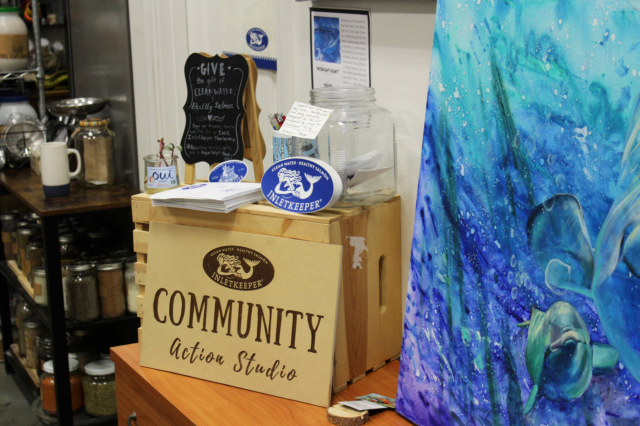 Informatin about Cook Inletkeeper is displayed next to artwork for sale as part of the “ART Sale 258” at the Cook Inletkeeper Community Action Studio on Thursday, Dec. 9, 2021 in Soldotna, Alaska. (Ashlyn O’Hara/Peninsula Clarion)