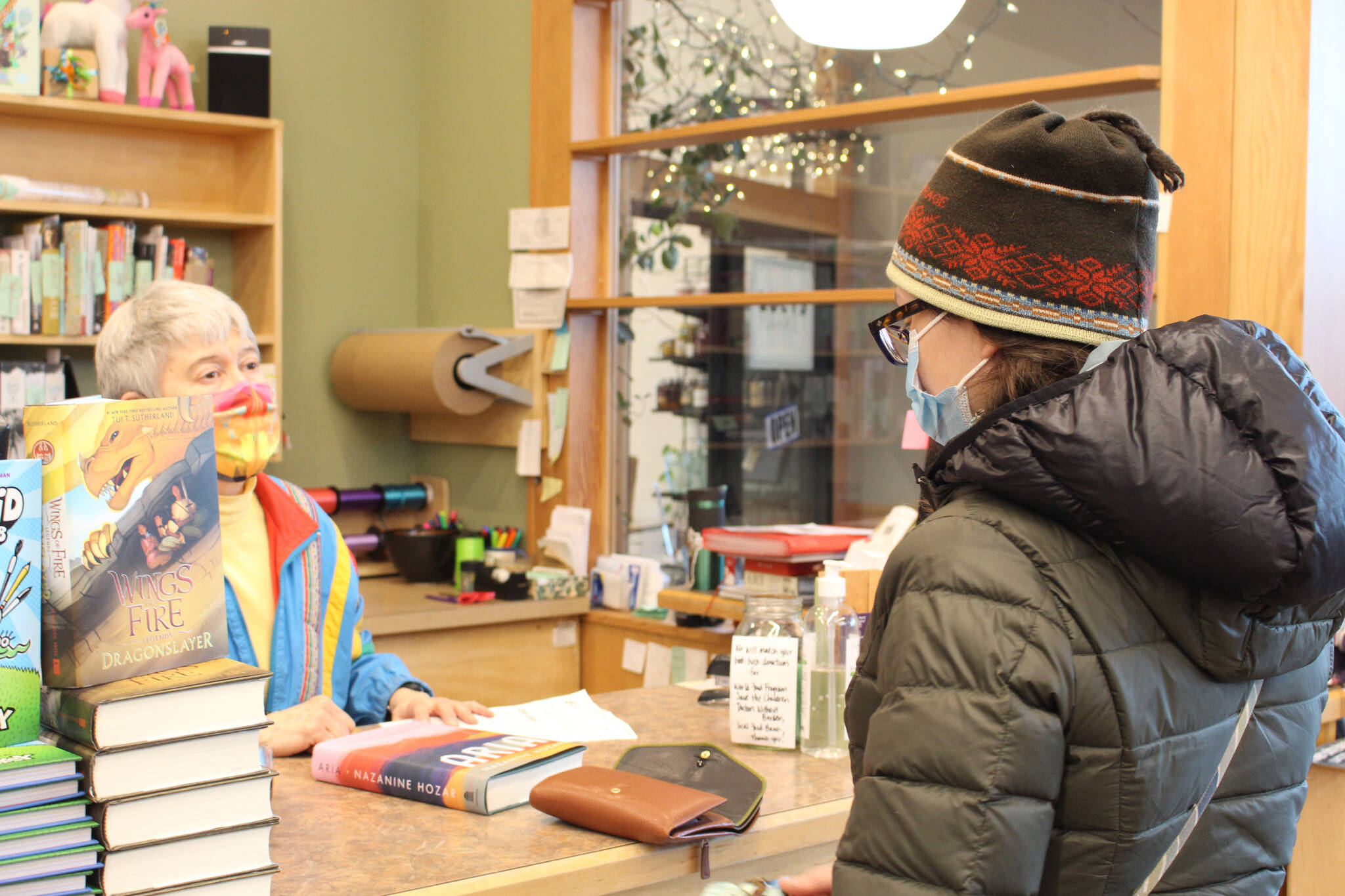 Maria Dixson, left, rings up a purchase by Sarah Pyhala, right, at River City Books in Soldotna, Alaska, on Jan. 2, 2021. (Photo by Brian Mazurek/Peninsula Clarion file)