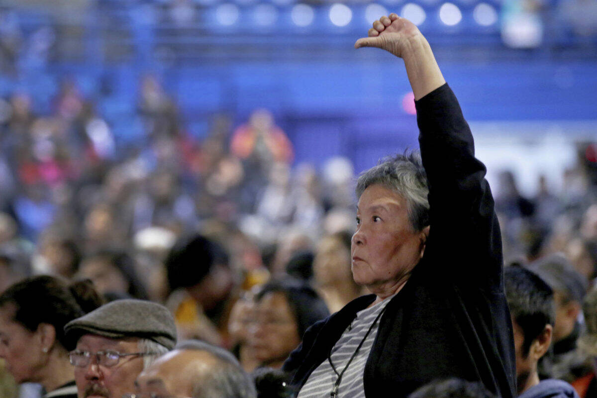 Eric Engman/Fairbanks Daily News-Miner via AP
Dorothy Thomson stands while giving a thumbs down as Gov. Mike Dunleavy gives his State of Alaska Address during the 2019 Alaska Federation of Natives Convention Thursday, Oct. 17, 2019. The 2019 convention was the last in-person convention as the COVID-19 pandemic has caused the meeting to go digital for the second year in a row.