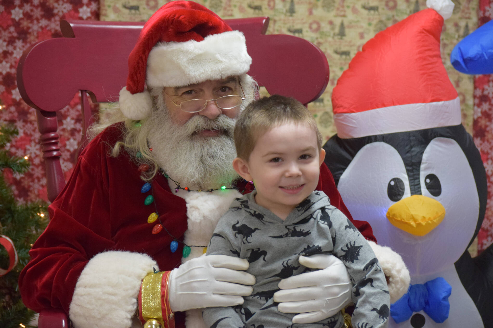 Brian Prather sits with Santa at the Nikiski Community Recreation Center on Saturday, Dec. 11, 2021, in Nikiski, Alaska. (Camille Botello/Peninsula Clarion)