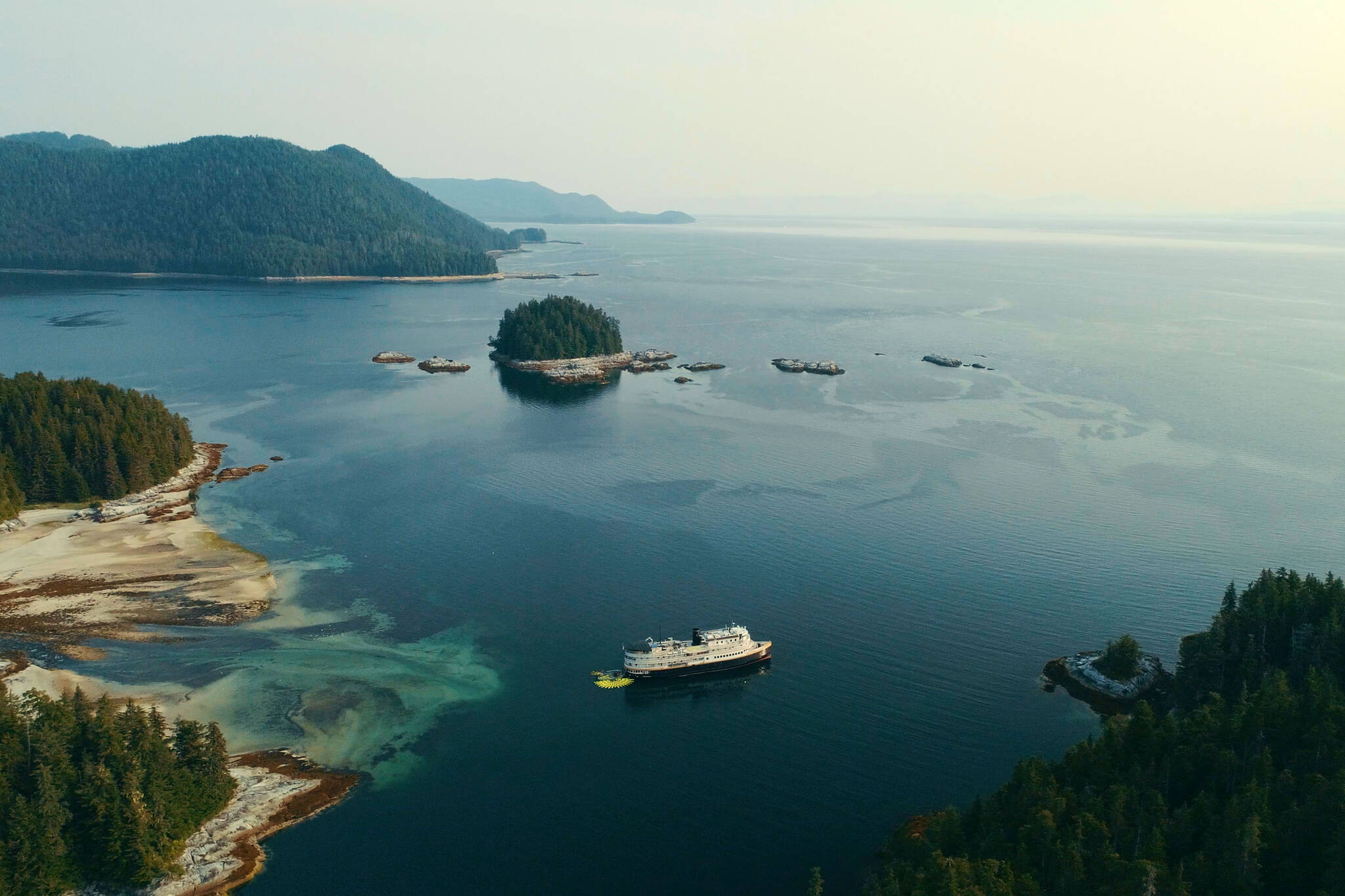 A Uncruise Adventures cruise ship, with a fleet of kayaks in the water behind it, in the Tongass National Forest. Uncruise, a boutique local cruise ship operator, has been vocal about the importance of the intact Tongass National Forest, or SeaBank, to its business. (Photo by Ben Hamilton/courtesy Salmon State)