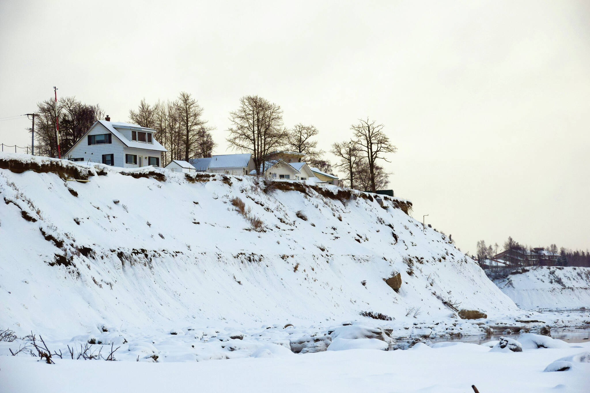 Buildings are perched above eroding bluffs on North Kenai Beach in Kenai, Alaska, on Wednesday, Jan. 19, 2022. The City of Kenai is receiving federal funds to address coastal erosion along sections of the bluff through the Infrastructure Investment and Jobs Act of 2021. (Photo by Camille Botello/Peninsula Clarion)