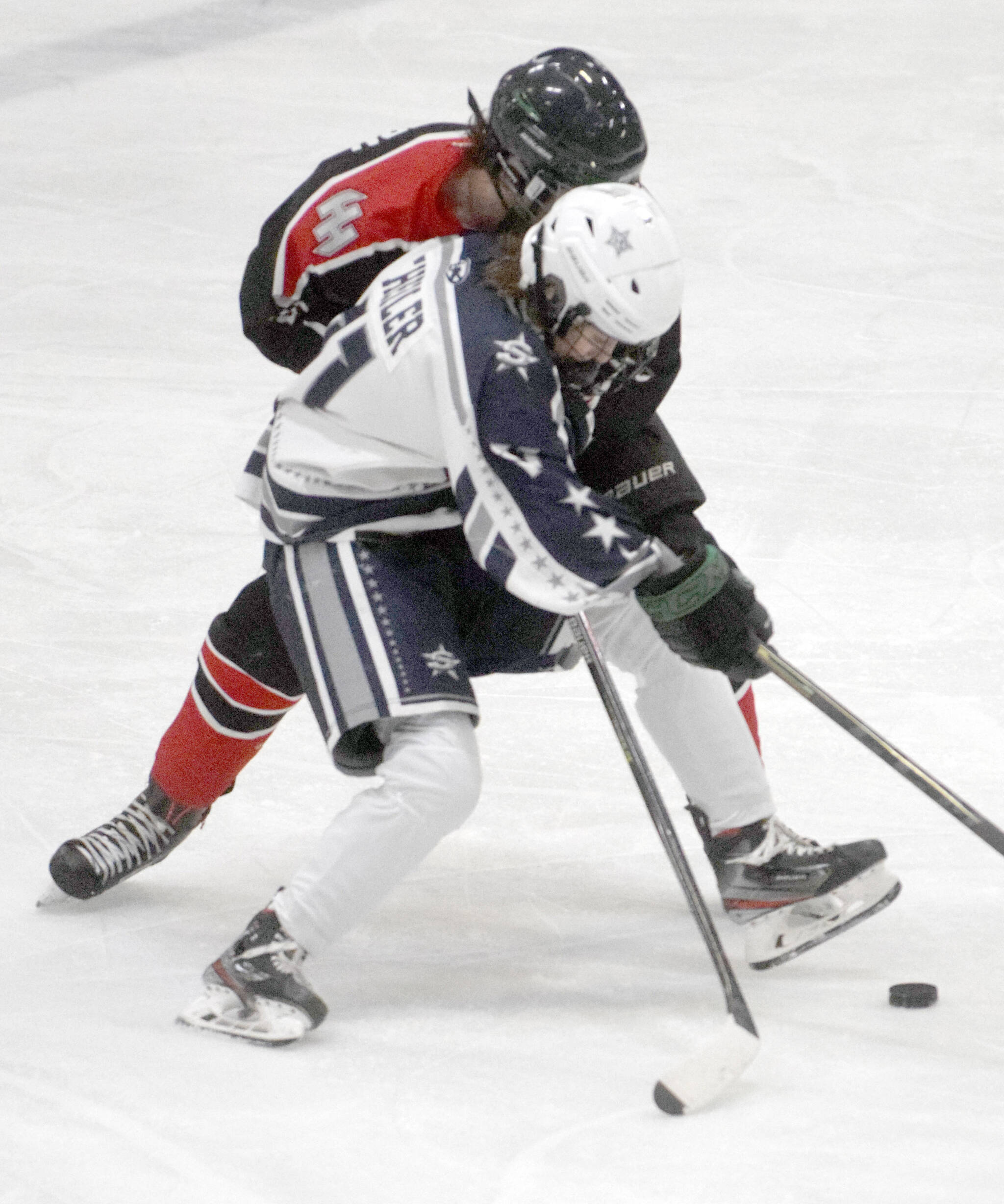 Soldotna’s Boone Theiler battles for the puck against Houston on Thursday, Jan. 20, 2022, at the Soldotna Regional Sports Complex in Soldotna, Alaska. (Photo by Jeff Helminiak/Peninsula Clarion)