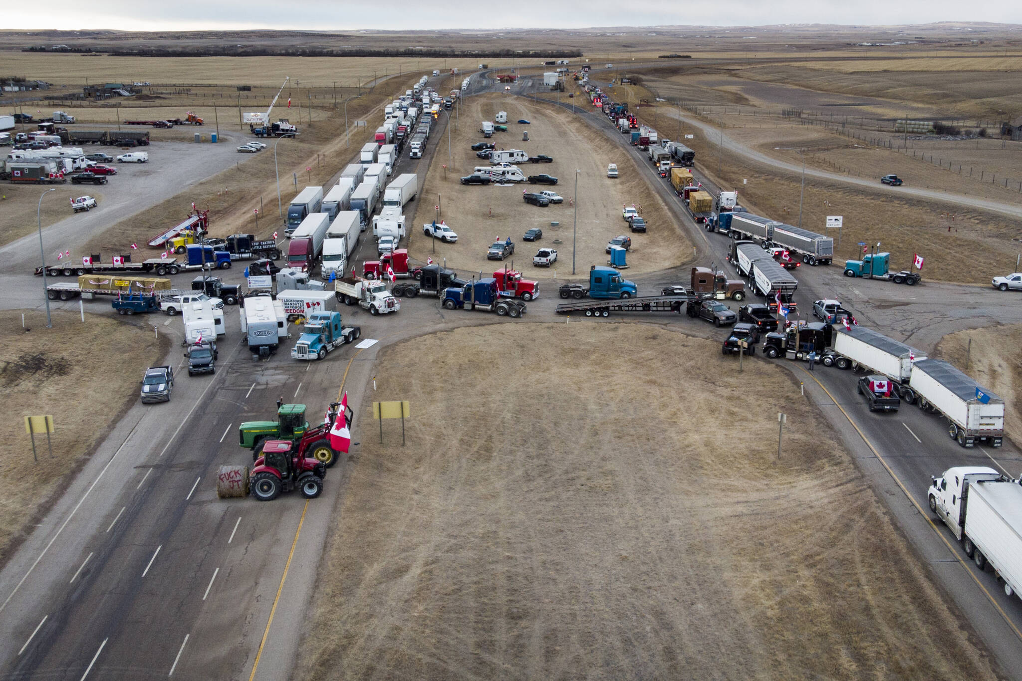 Anti-COVID-19 vaccine mandate demonstrators gather as a truck convoy blocks the highway at the busy U.S. border crossing in Coutts, Alberta, Canada, Monday, Jan. 31, 2022. (Jeff McIntosh/The Canadian Press via AP)