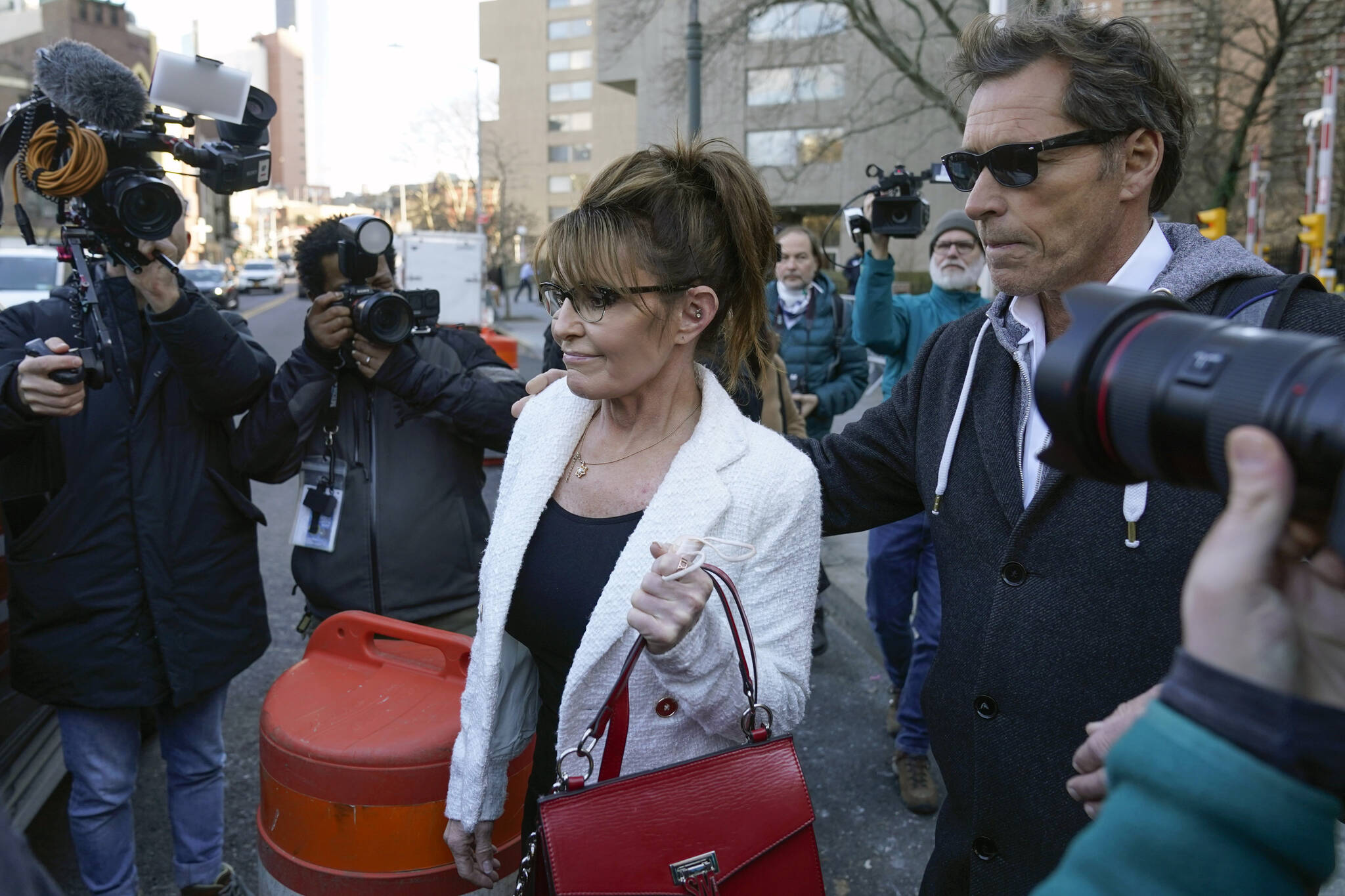 Sarah Palin is escorted to her car by Ron Duguay after leaving the courthouse in New York, Thursday, Feb. 10, 2022. Former Alaska Gov. Sarah Palin told a jury Thursday she felt like she was at the mercy of a “Goliath” when she first learned a 2017 New York Times editorial suggested her campaign rhetoric helped incite a mass shooting. (AP Photo/Seth Wenig)