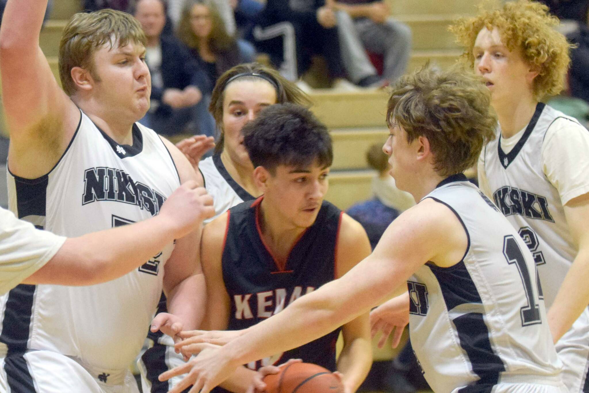 Kenai Central's Jakob Kvasnikoff tries to escape the trap of Nikiski's Drew Handley and Isaiah Daniels on Tuesday, Feb. 15, 2022, at Nikiski High School in Nikiski, Alaska. (Photo by Camille Botello/Peninsula Clarion)