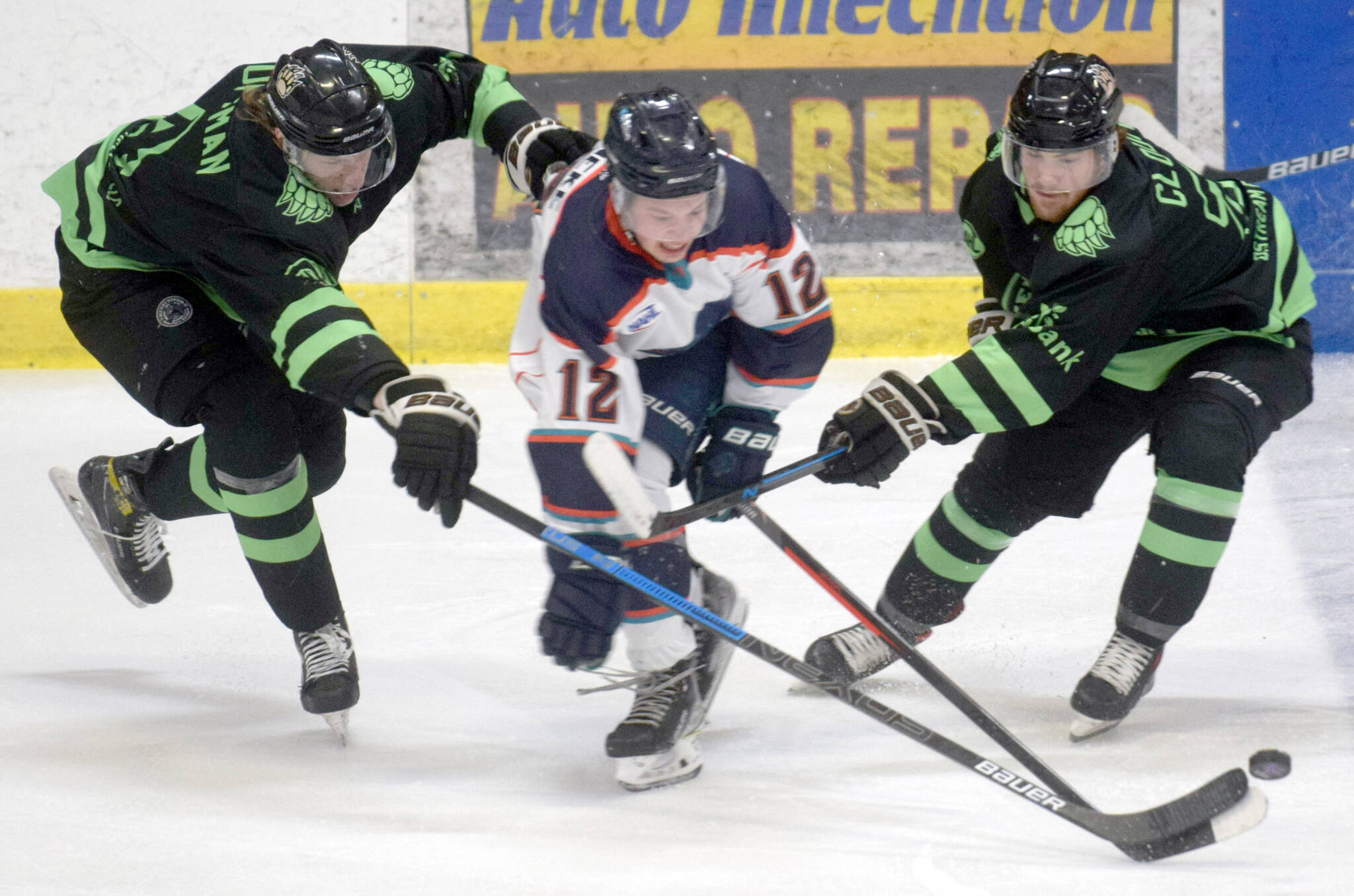 Caleb Huffman and Carter Cloutier of the Kenai River Brown Bears battle Jackson Reineke of the Anchorage Wolverines for the puck Friday, Feb. 18, 2022, at the Soldotna Regional Sports Complex in Soldotna, Alaska. (Photo by Camille Botello/Peninsula Clarion)