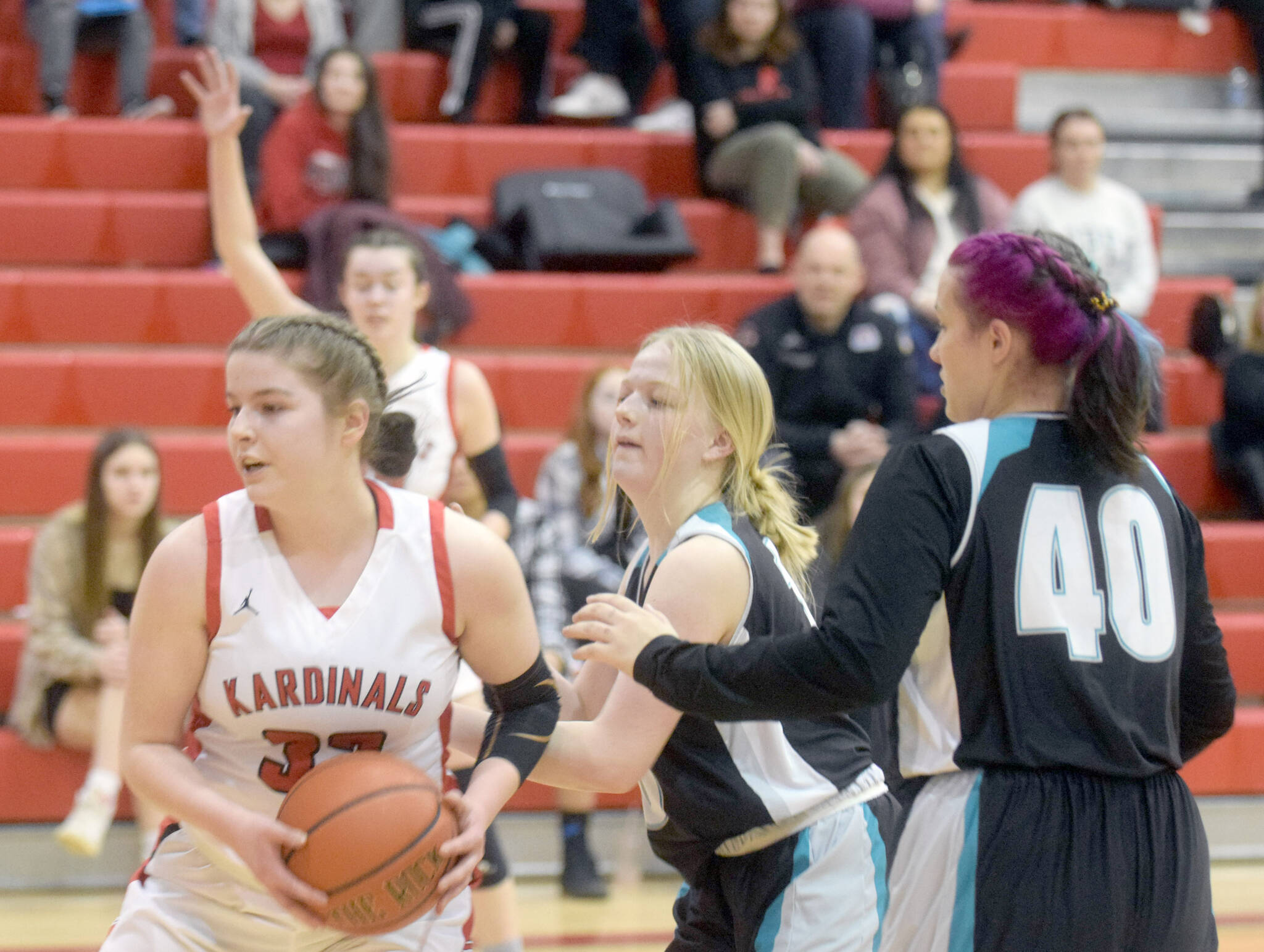 Kenai Central’s Denali Bernard keeps the ball from Nikiski’s Avery White and Destiny Langston on Tuesday, Feb. 22, 2022, at Kenai Central High School in Kenai, Alaska. (Photo by Camille Botello/Peninsula Clarion)