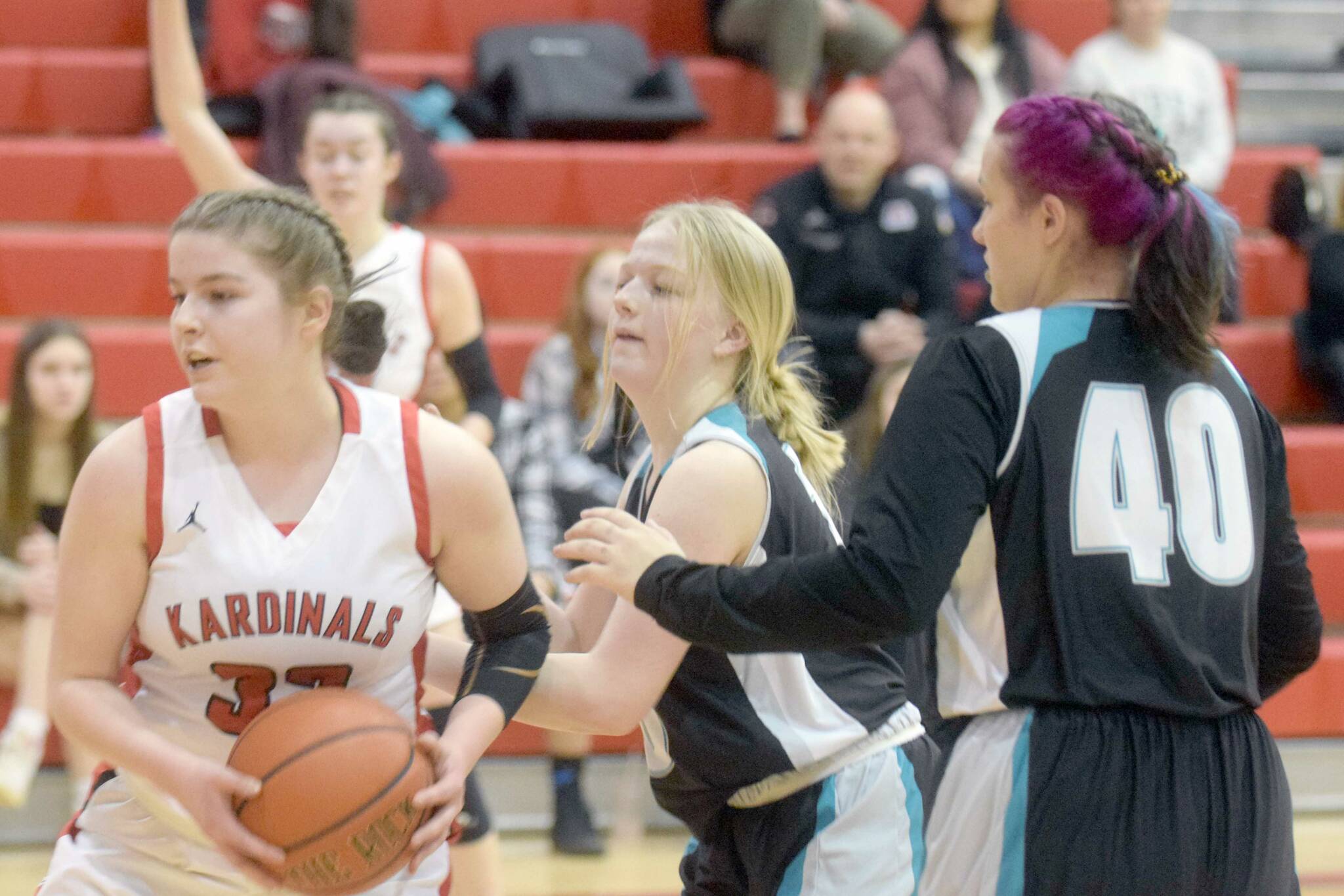 Kenai Central's Denali Bernard keeps the ball from Nikiski's Avery White and Destiny Langston on Tuesday, Feb. 22, 2022, at Kenai Central High School in Kenai, Alaska. (Photo by Camille Botello/Peninsula Clarion)