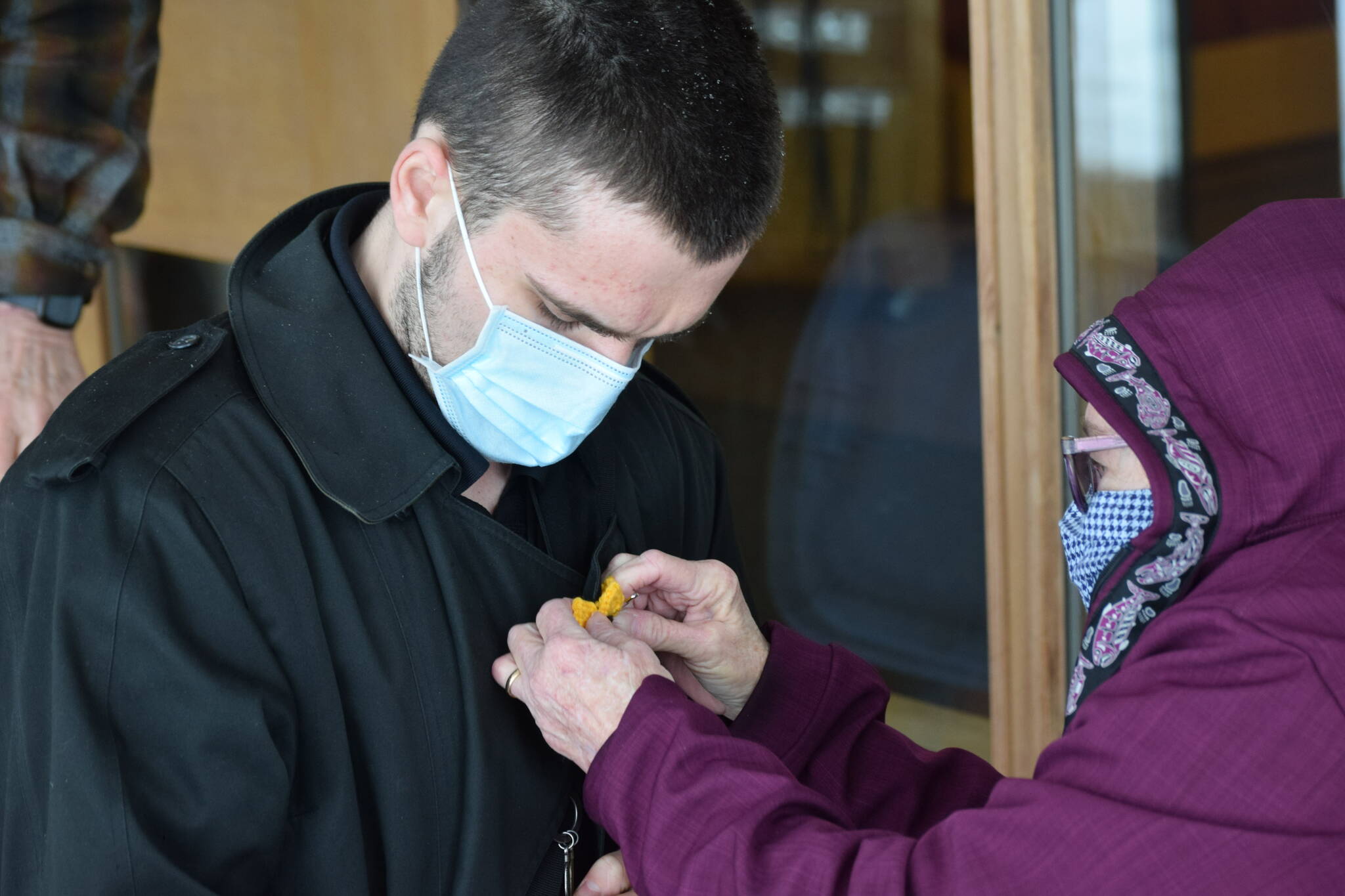 Kim Keck gives James Redmon a crochet sunflower pendant during the Many Voices Ukraine vigil on Saturday, March 5, 2022, in Soldotna, Alaska. (Camille Botello/Peninsula Clarion)