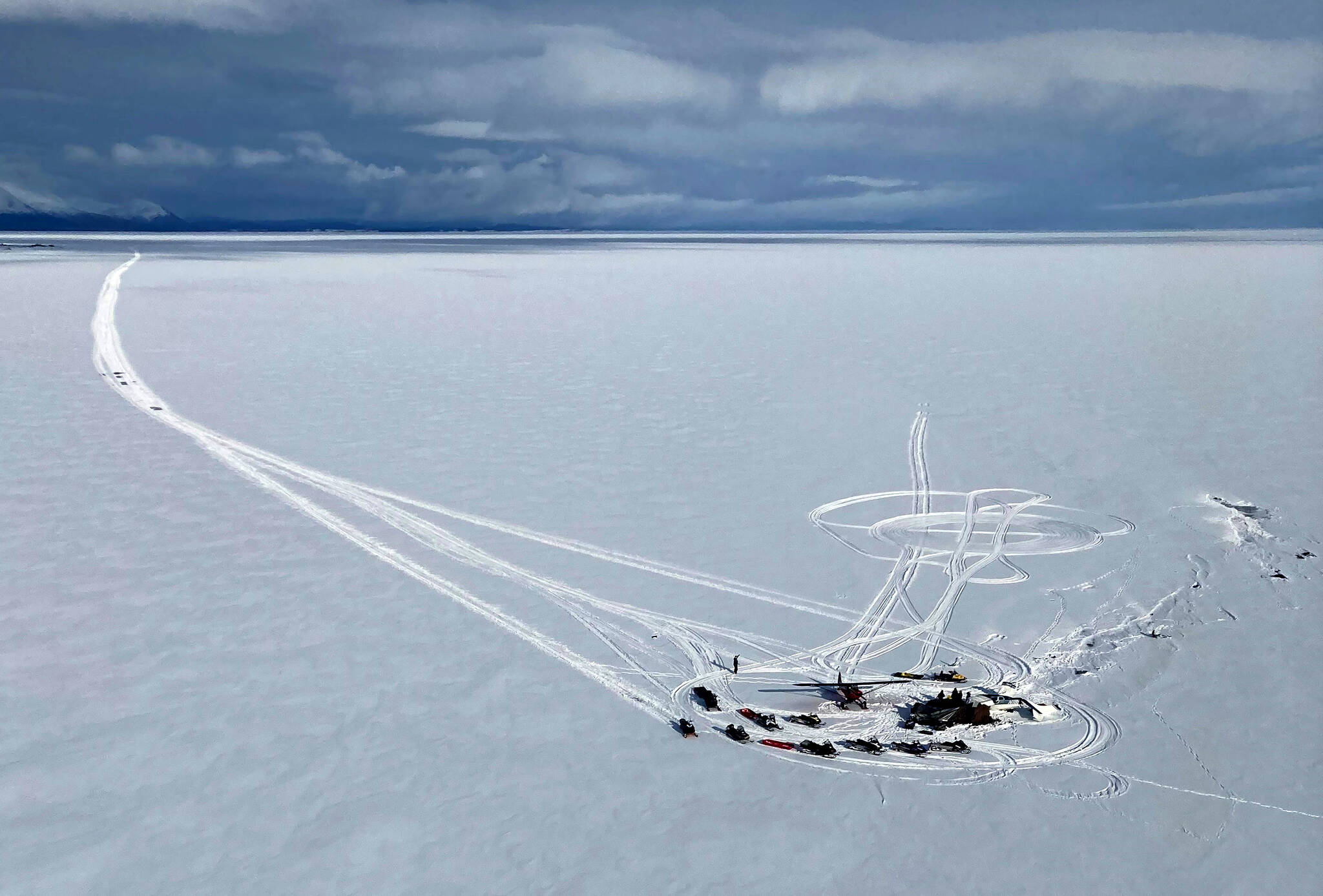 In this aerial photo provided by Alaska State Troopers, an Alaska Air National Guard helicopter arrives at a frozen lake that was the scene of a small plane crash on Saturday, March 5, 2022, near Iliamna, Alaska. Authorities say the five people on board the plane were injured. (Trooper Travis Lons/Alaska State Troopers via AP)