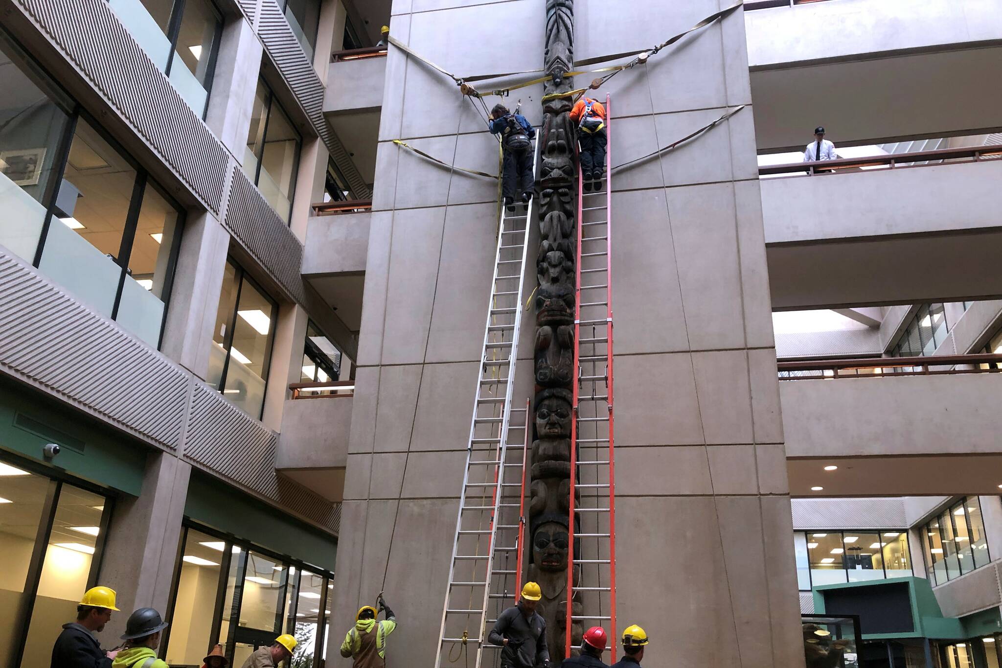 The Wooshkeetaan Kootéeyaa totem pole was re-installed at its new home in the atrium of the State Office Building on Friday, March 11, 2022. Workers from Alaska Electric Light and Power helped install the pole. (Peter Segall / Juneau Empire)