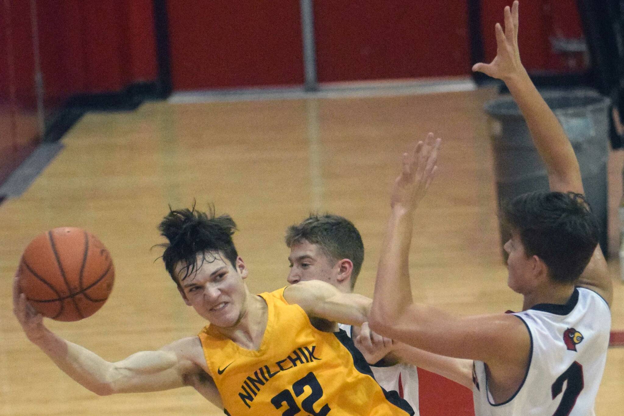 Ninilchik’s Justin Trail saves the ball in front of Kenai Central’s Luke Armstrong and Eli McCubbins on Saturday, March 5, 2022, at Kenai Central High School in Kenai, Alaska. (Photo by Jeff Helminiak/Peninsula Clarion)