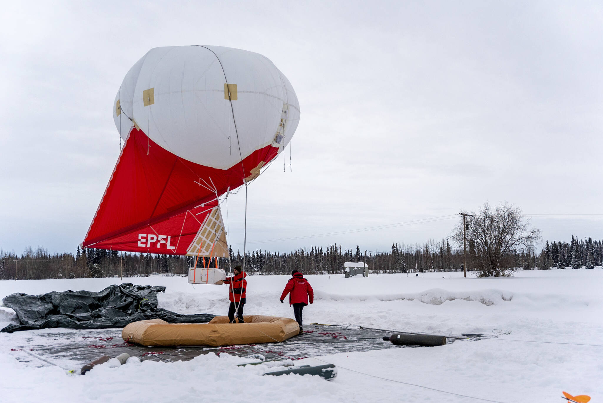 This Feb. 21, 2022, photo provided by the University of Alaska Fairbanks Geophysical Institute shows Swiss team members working with a tethered balloon and payload used to measure different characteristics of aerosols and trace gases in the atmosphere over Fairbanks, Alaska. Over seven weeks this winter, nearly 50 scientists from the continental U.S. and Europe descended on Fairbanks to study the sources of air pollution. (Daniel Walker/University of Alaska Fairbanks Geophysical Institute via AP)