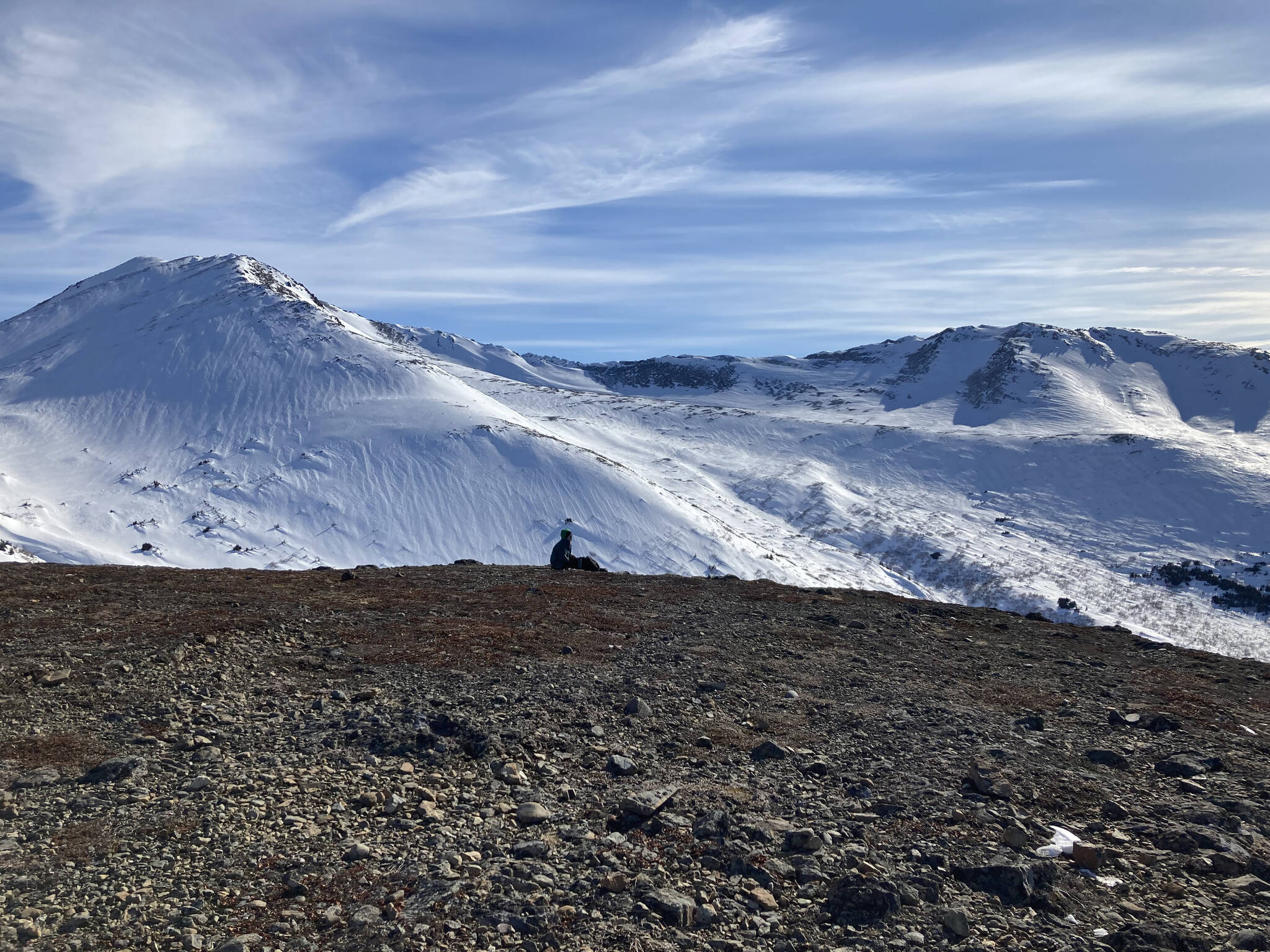 A hiker rests near the peak of Near Point Trail in Anchorage, Alaska, on March 20, 2022. (Camille Botello/Peninsula Clarion)