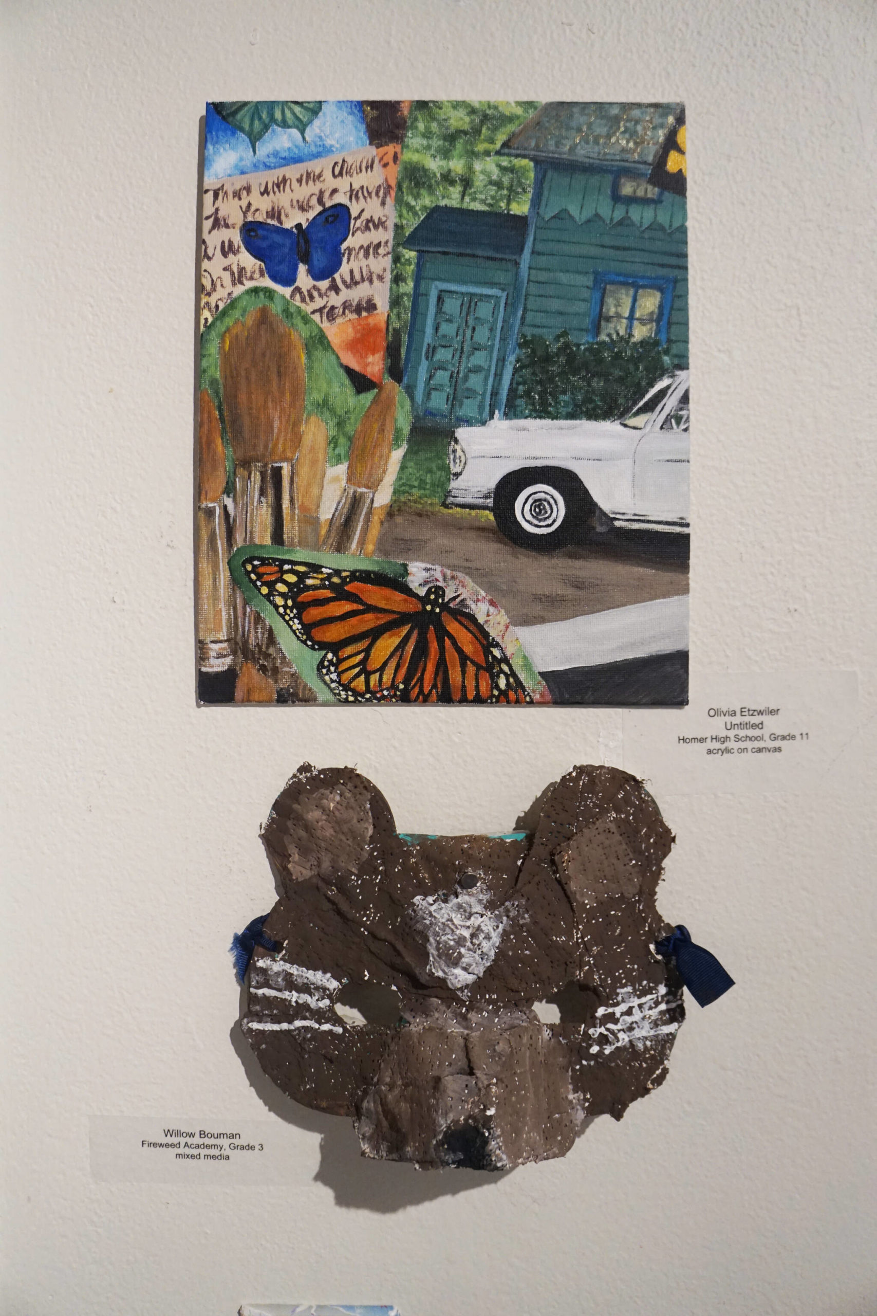 Grade 11 Homer High School student Olivia Etzwiler’s “Untitled,” is at top, and grade 3 Fireweed Academy student Willow Bouman’s mask is at bottom. (Photo by Michael Armstrong/Homer News)