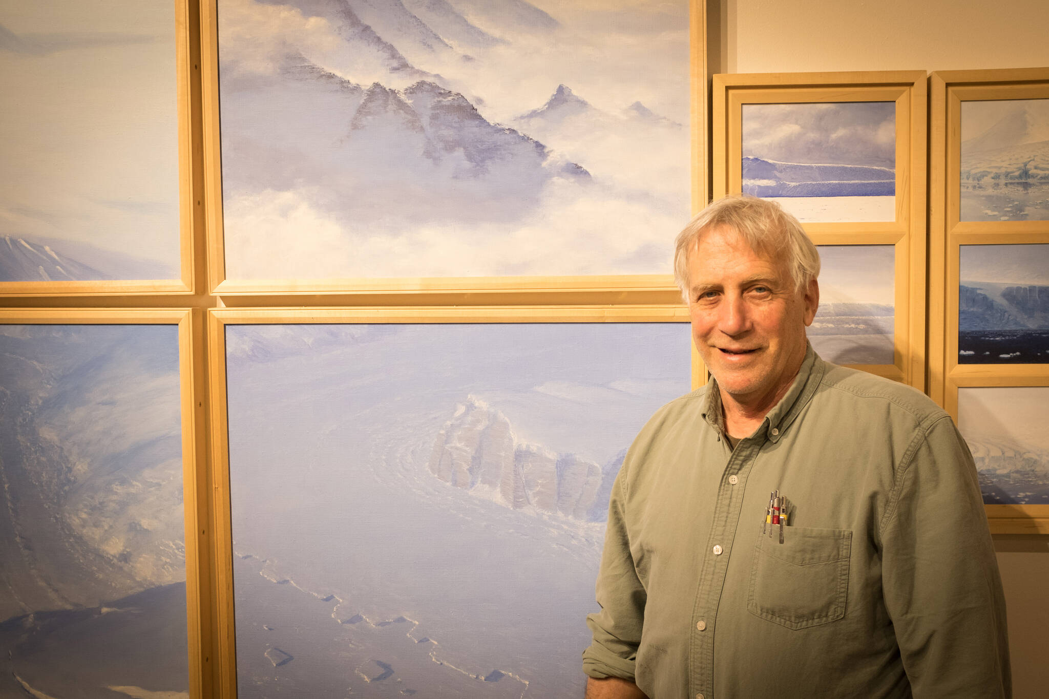 Photo by Sean McDermott 
David Rosenthal poses for a portrait in front of paintings from his time in Antarctica at the Pratt Museum & Park in Homer.