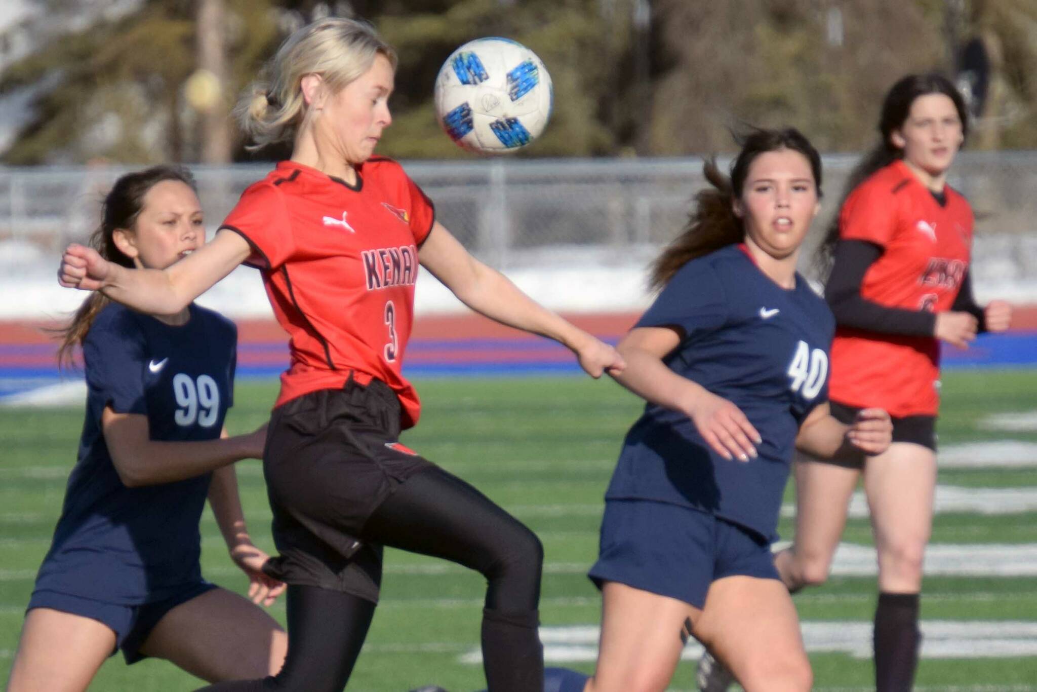 Kenai Central's Cali Holmes tries to clear the ball from Soldotna's Caleigh Glassmaker and Caylee Uribe-Koivisto on Thursday, April 14, 2022, at Soldotna High School in Soldotna, Alaska. (Photo by Jeff Helminiak/Peninsula Clarion)