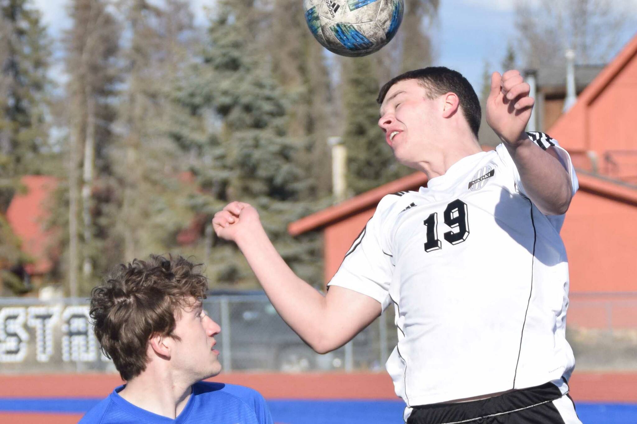 Nikiski's Truit McCaughey heads the ball over Soldotna's Silas Larsen on Wednesday, April 27, 2022, at Justin Maile Field at Soldotna High School in Soldotna, Alaska. (Photo by Jeff Helminiak/Peninsula Clarion)