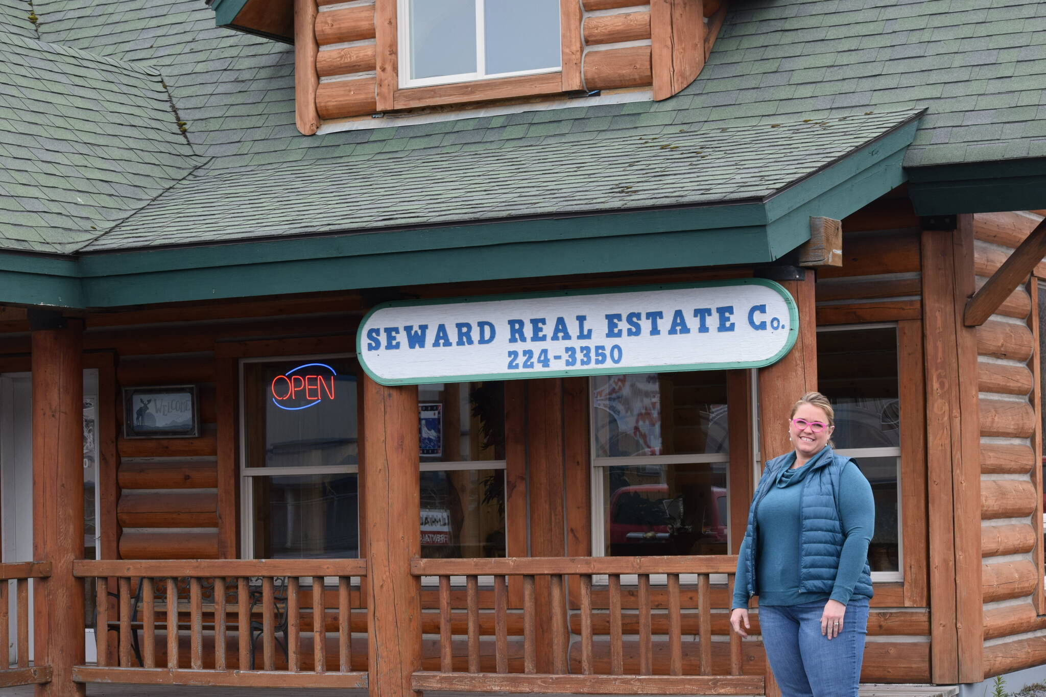 Real estate agent Jena Petersen stands in front of Seward Real Estate Company in Seward, Alaska, on Tuesday, May 3, 2022. (Camille Botello/Peninsula Clarion)