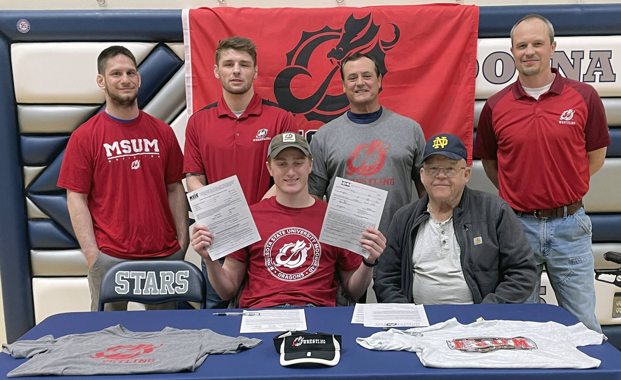 Wayne Mellon, seated at the table with stepfather Michael Gebhard, signs a National Letter of Intent on Tuesday, May 4, 2022, at Soldotna High School in Soldotna, Alaska. In back are SoHi wrestling coaches Aaron Gordon, Logan Parks, Neldon Gardner and Pete Dickinson. (Photo provided)