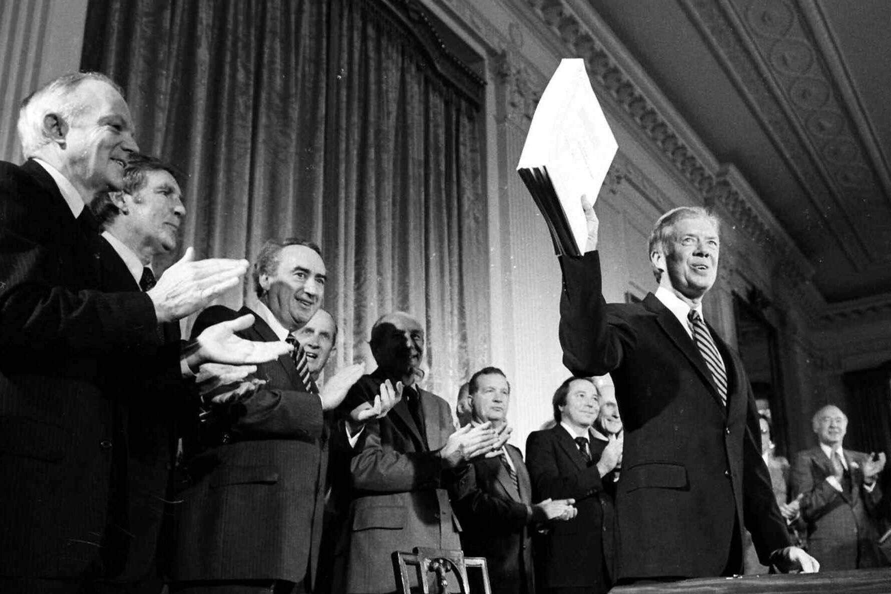 President Jimmy Carter holds up the Alaska National Interest Lands Conservation Act, which declared 104 million acres in Alaska as national parks, wildlife refuges and other conservation categories, after signing it into law at a ceremony at the White House in Washington, on Dec. 2, 1980. Carter on Monday, May 9, 2022, took the unusual step of weighing in on a court case involving his landmark conservation act and a remote refuge in Alaska. Carter filed a amicus brief in the longstanding legal dispute over efforts to build a road through the refuge, worried that the latest decision to allow a gravel road to provide residents access to an all-weather airport for medical evacuations goes beyond this one case and could allow millions of acres (hectares) to be opened for “adverse development.” (AP Photo, File)