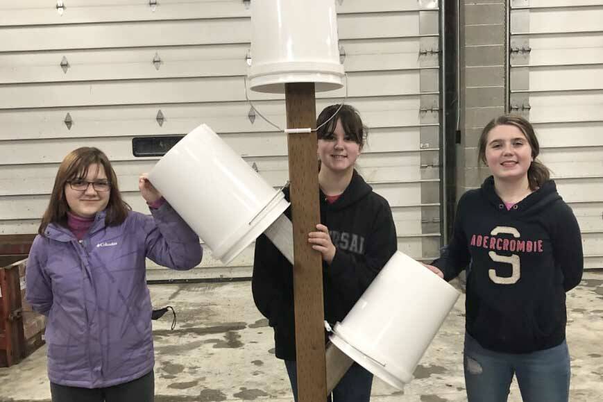 Three Girl Scouts from Troop 210 hold their first Bucket Tree after finishing construction with the help of Davis Block employees. (Photo by Leah Eskelin)