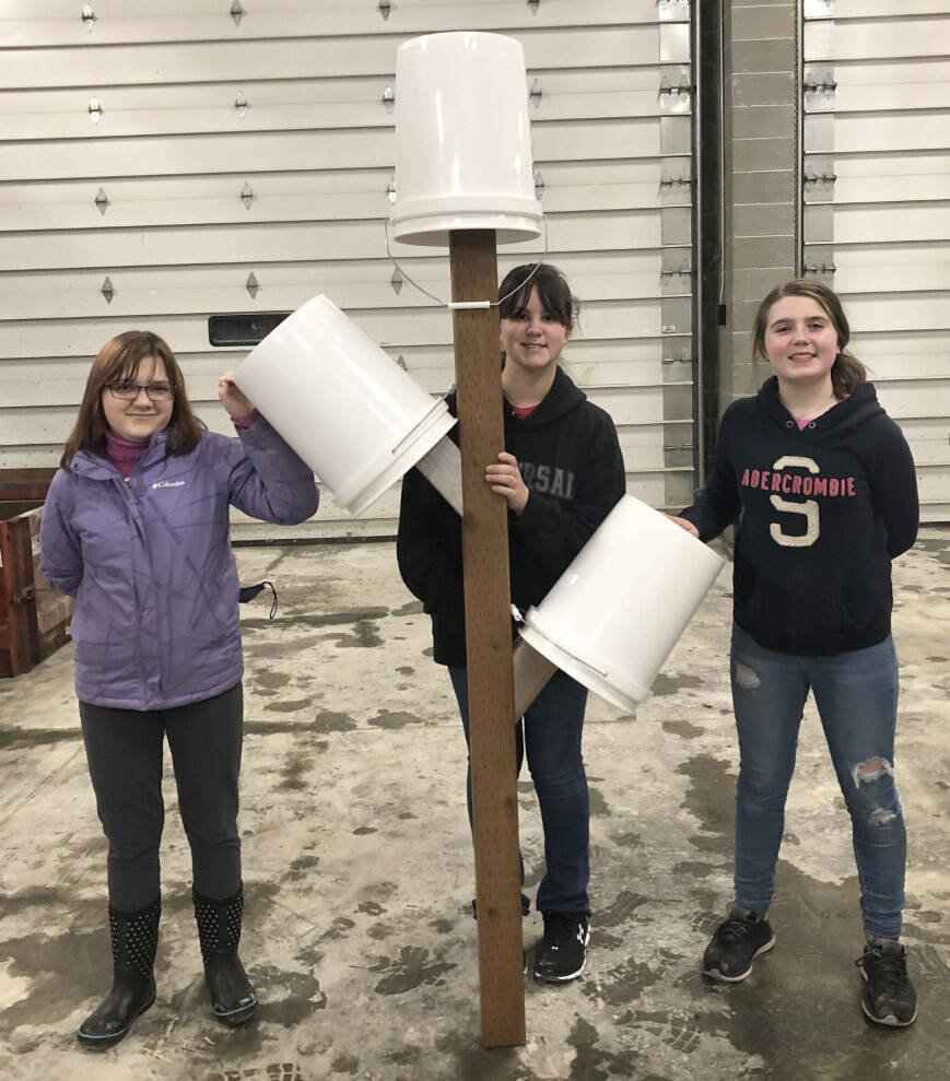 Three Girl Scouts from Troop 210 hold their first Bucket Tree after finishing construction with the help of Davis Block employees. (Photo by Leah Eskelin)