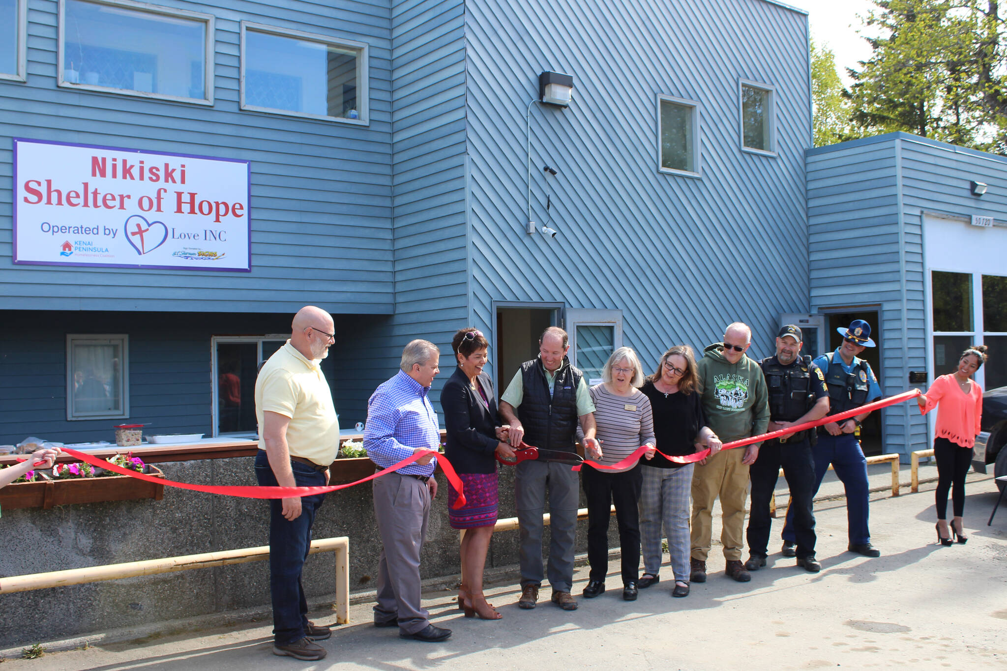 Project stakeholders cut a ribbon at the Nikiski Shelter of Hope on Friday, May 20, 2022, in Nikiski, Alaska. (Ashlyn O’Hara/Peninsula Clarion)