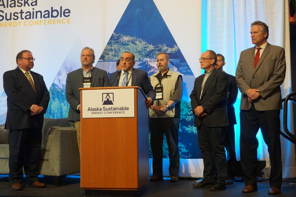 Tony Izzo, CEO of Matansuka Electric Association, stands with other utility executives on May 25 to describe a $200 million project to upgrade transmission lines along Alaska’s Railbelt. The announcement was made at the Alaska Sustainable Energy Conference in Anchorage. Curtis Thayer, executive director of the Alaska Energy Authority, is at the far left; Gov. Mike Dunleavy is at the far right. (Photo by Yereth Rosen/Alaska Beacon)