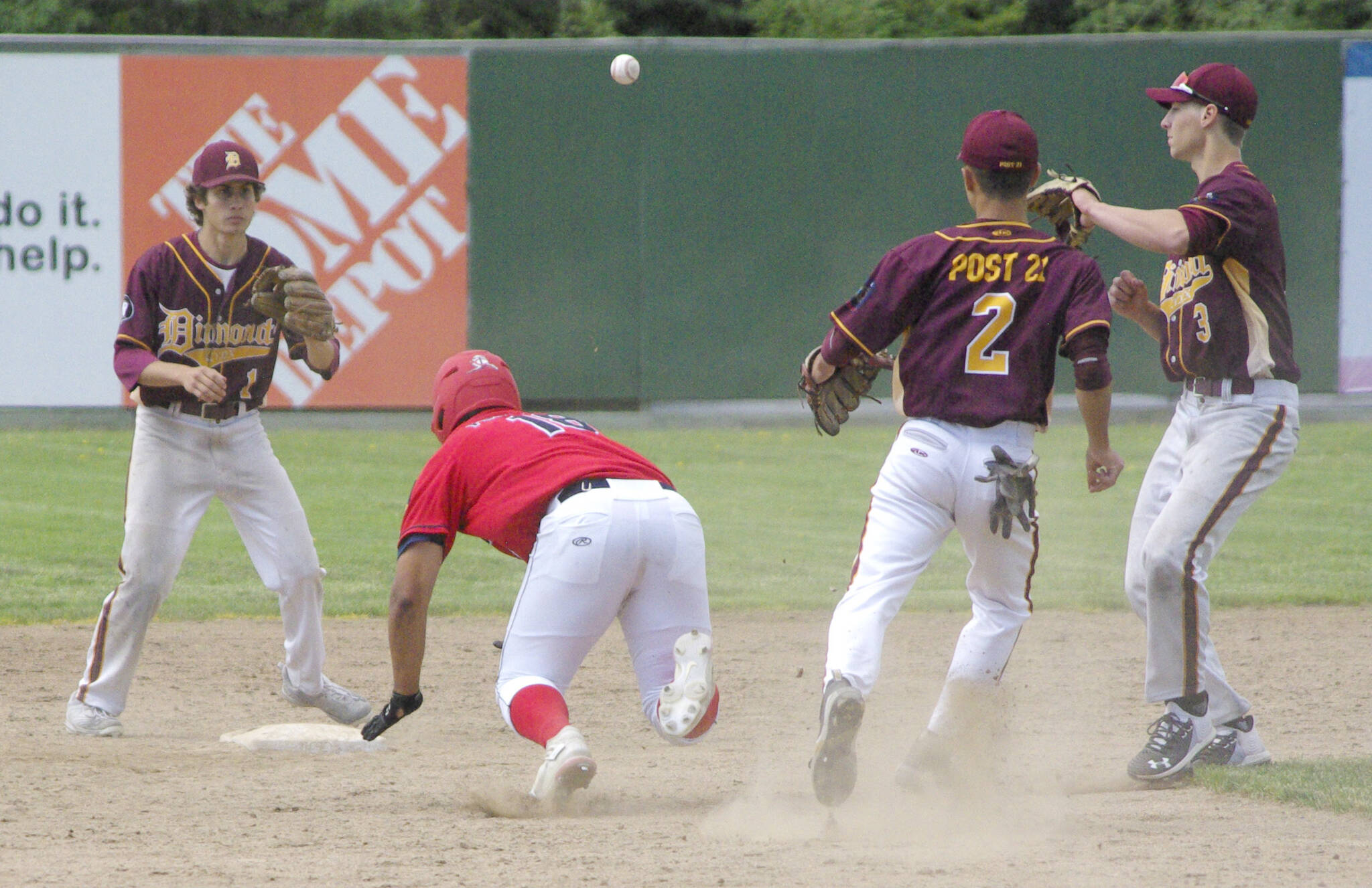 Atticus Gibson of the Post 20 Twins slides under the tag of Dimond's Shane Stephan to get out of a rundown Saturday, June 11, 2022, at Coral Seymour Memorial Park in Kenai, Alaska. (Photo by Jeff Helminiak/Peninsula Clarion)