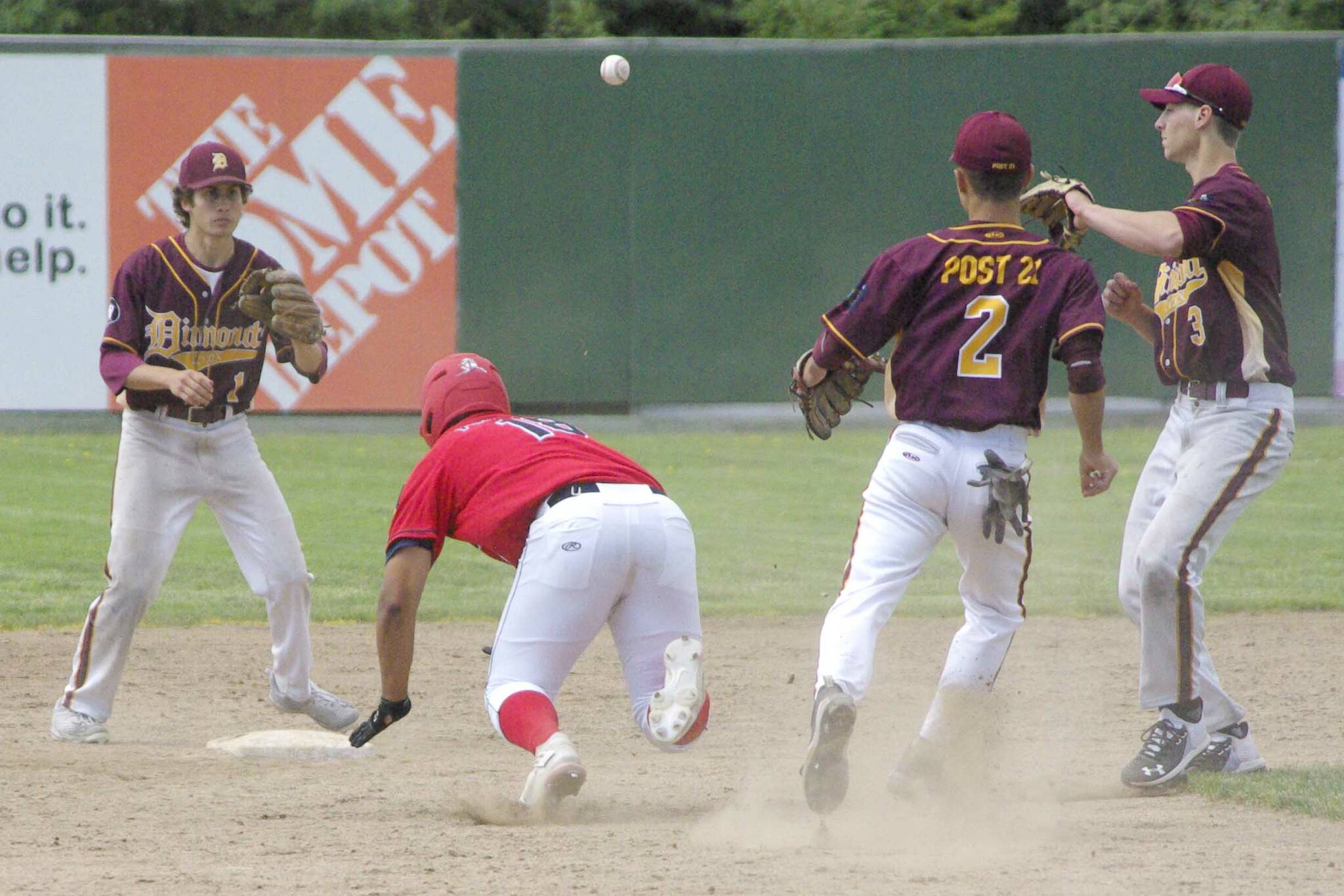 Atticus Gibson of the Post 20 Twins slides under the tag of Dimond's Shane Stephan to get out of a rundown Saturday, June 11, 2022, at Coral Seymour Memorial Park in Kenai, Alaska. (Photo by Jeff Helminiak/Peninsula Clarion)