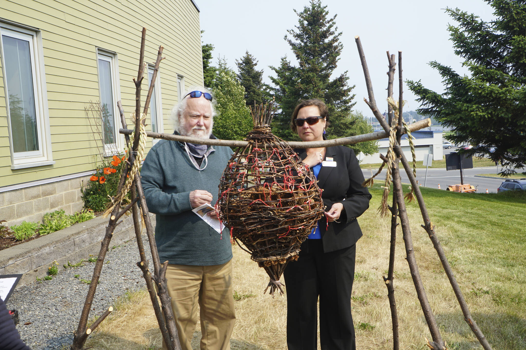 Pastor Lisa Talbott, right, of Homer United Methodist Church, and Joseph Talbott, left, place spruce cones in rememberance of Anesha “Duffy” in the Sphere of Love, a sculpture by Mavis Muller. Pastor Talbott delivered a prayer at the dedication of the Loved & Lost Memorial Bench on Sunday, June 12, 2022, at the Homer Public Library in Homer, Alaska. (Photo by Michael Armstrong/Homer News)