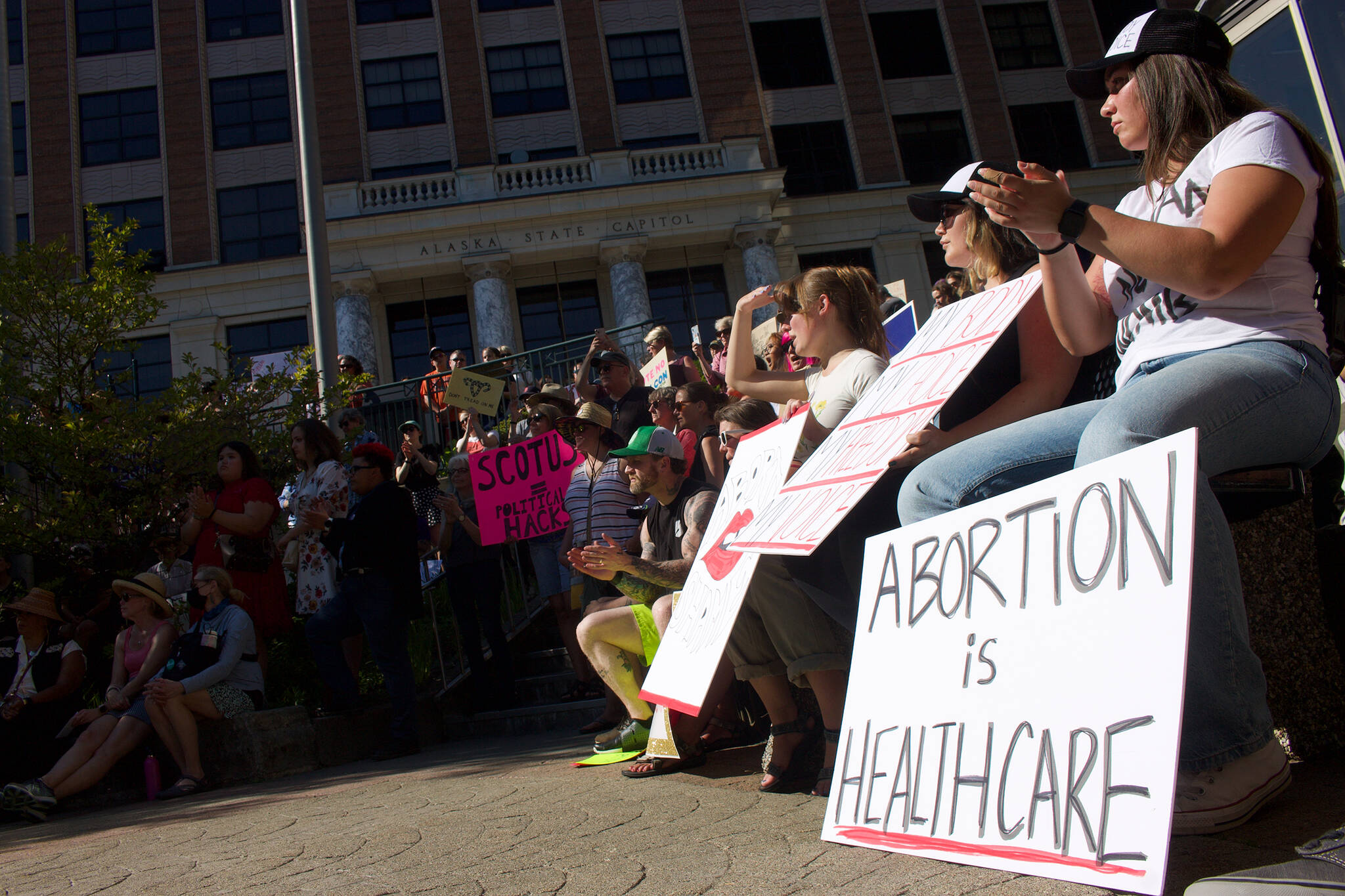 A crowd of people protesting near the Alaskan State Capitol clap at one of the many speakers at the protest, Saturday in Juneau. (Clarise Larson / Juneau Empire)