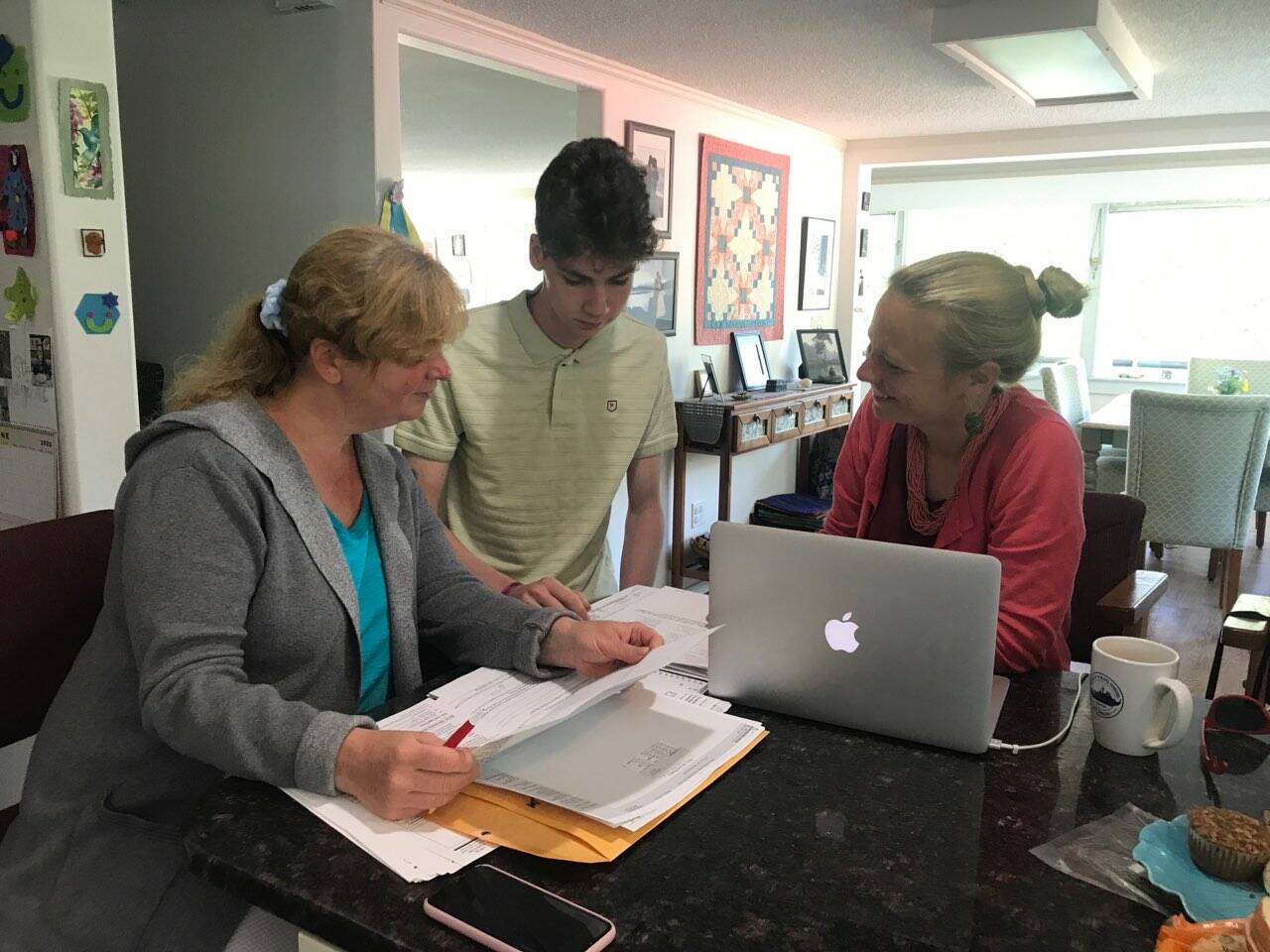 Heather Parker, right a Sponsor Circles member, helping Iryna and Ivan Hrynchenko with paperwork after the Ukrainian mother and son arrived in Juneau last Saturday, June 25, 2022. Five local residents formed a local chapter of Social Circles, a nationwide organization working to resettle refugees from Afghanistan and Ukraine in the U.S. (Courtesy Photo / Joyanne Bloom)